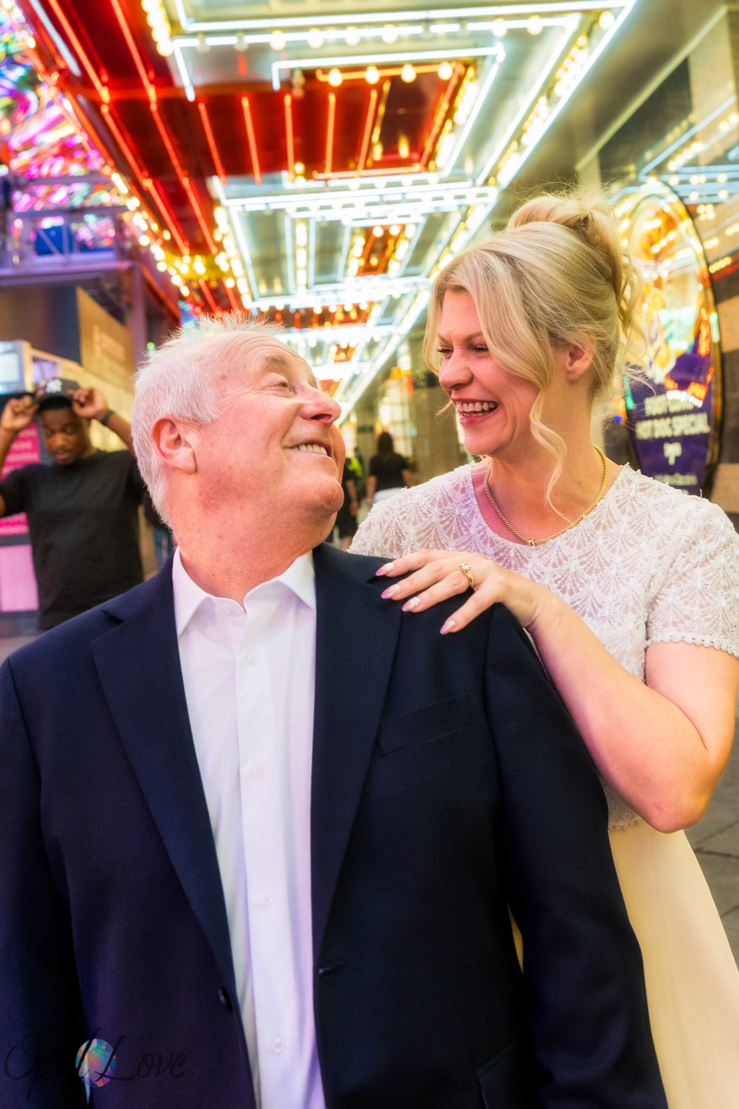 Bride laughing beside groom beneath bright neon casino lights on Fremont Street.