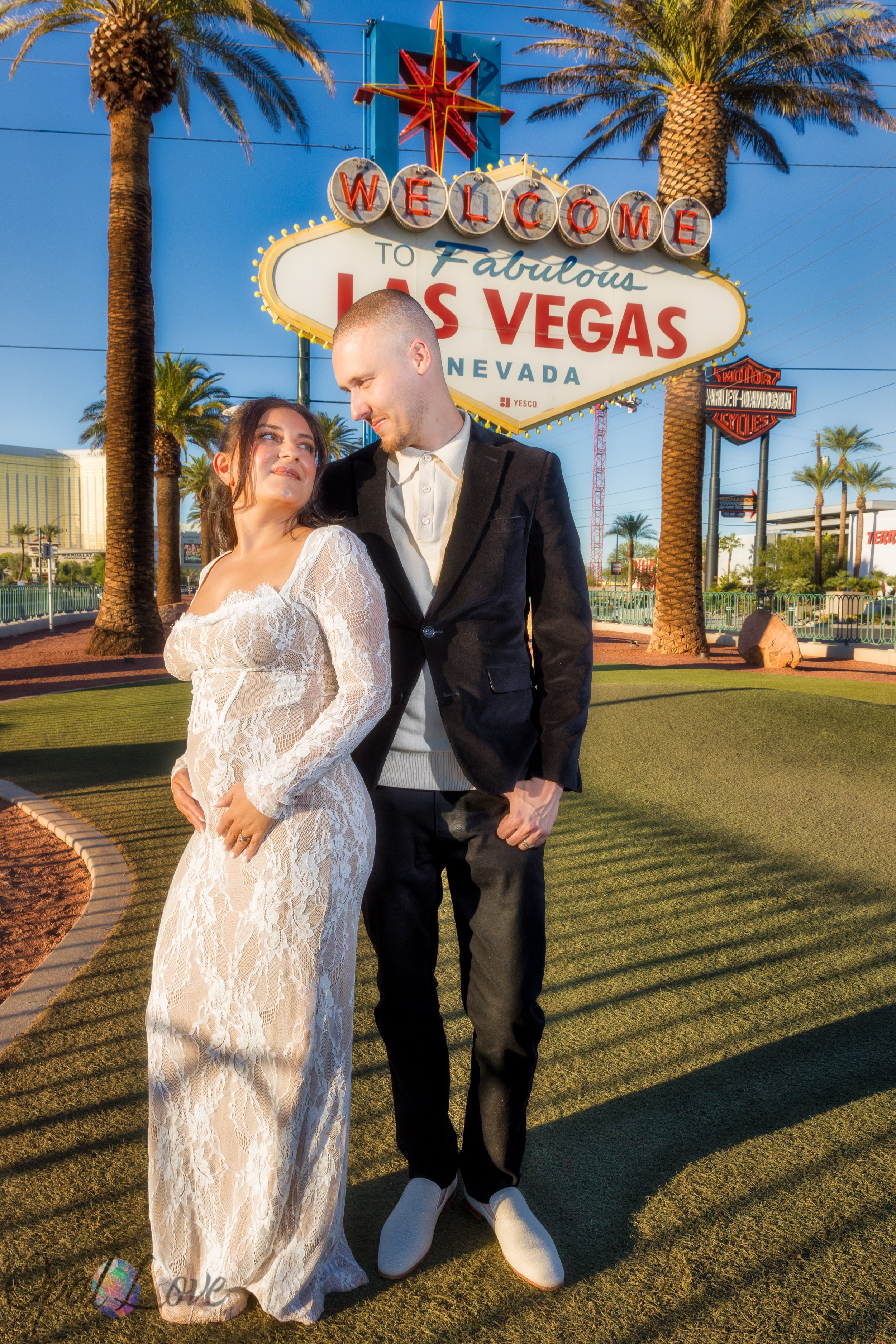 Couple smiling at each other with the Welcome to Las Vegas Sign glowing behind them.