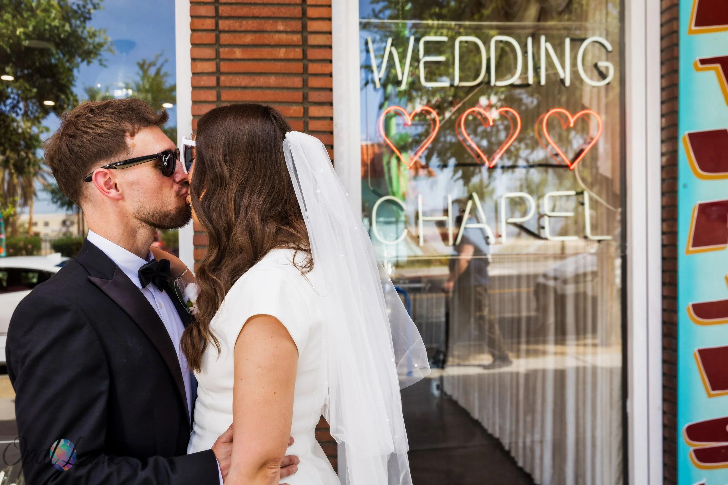 Bride and groom kissing outside A Sure Thing Wedding Chapel neon wedding sign in Downtown Las Vegas