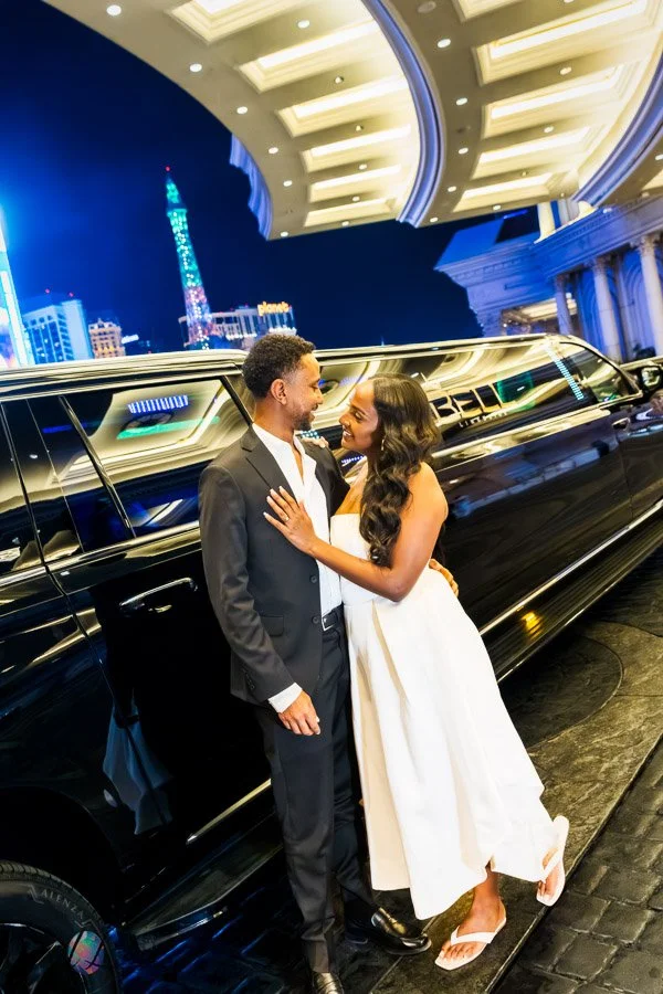 Couple embracing beside a limousine at Caesars Palace in Las Vegas at night.