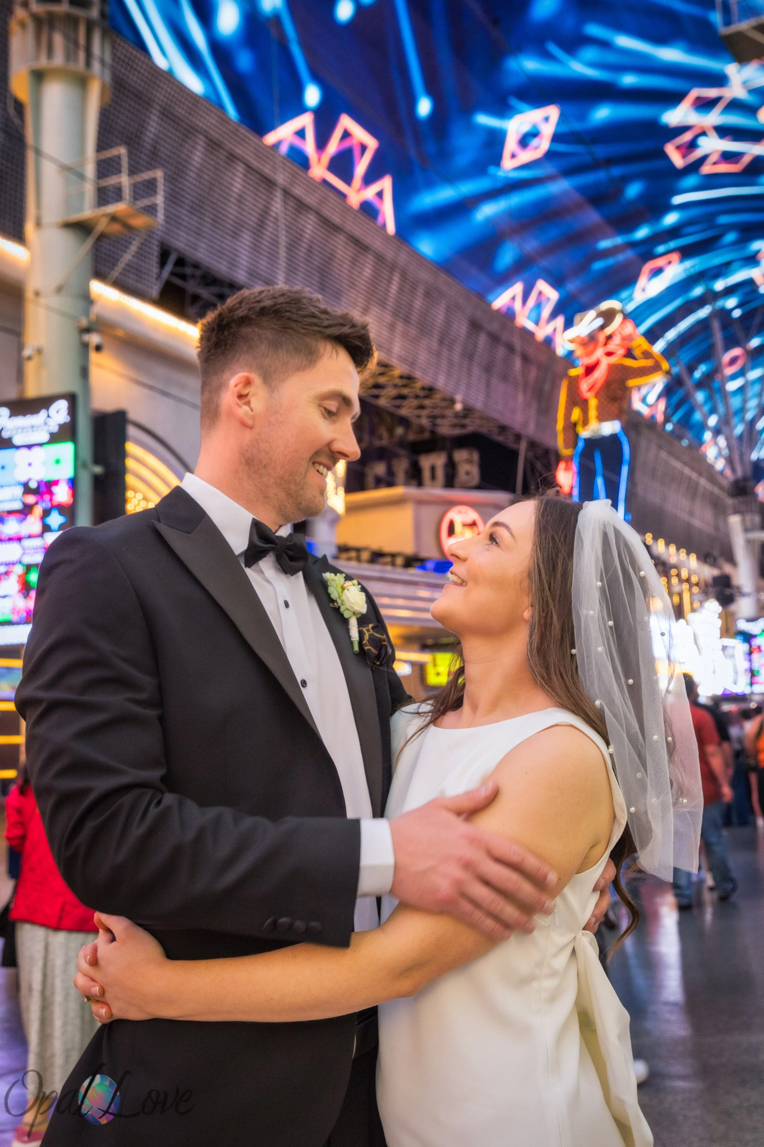 Bride and groom embracing under Fremont Street neon cowboy sign
