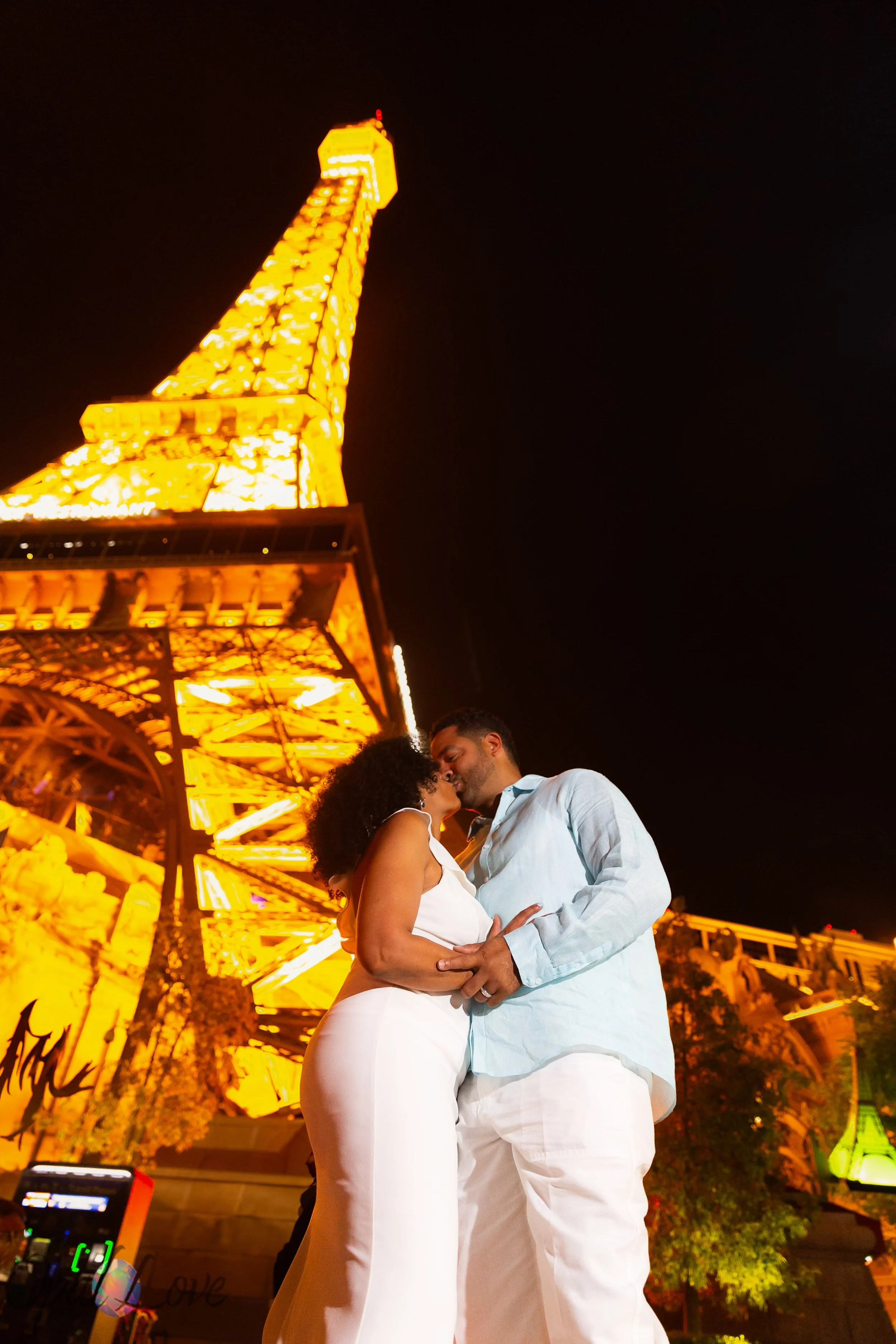 Couple embracing with the illuminated Eiffel Tower at Paris Las Vegas in the background captured by Opal Love Photography.