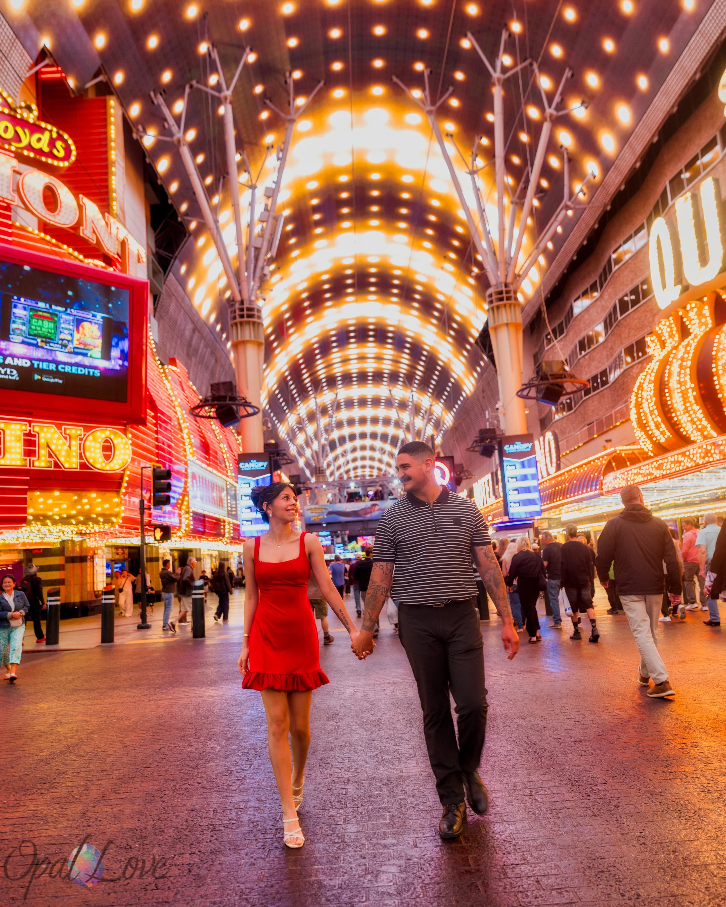 Couple walks hand in hand beneath the lights of Fremont Street