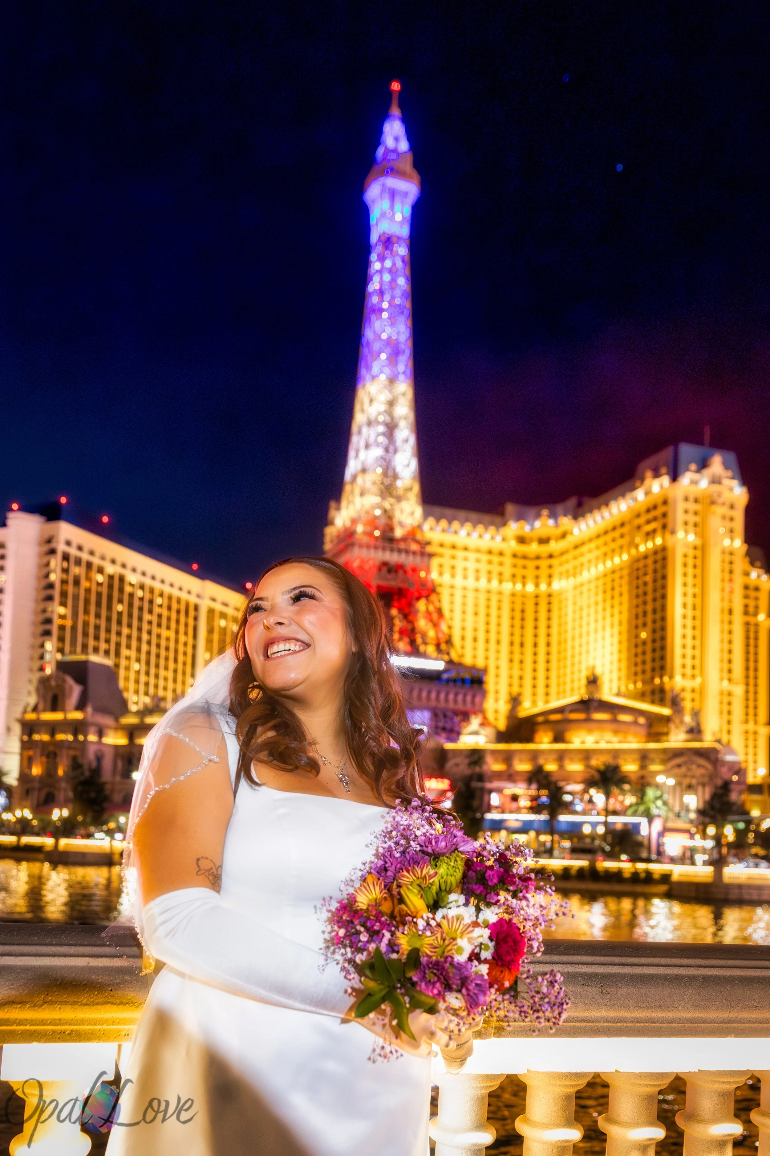 Bride, with big smile holding a bouquet at the Bellagio with the Eiffel Tower in the background