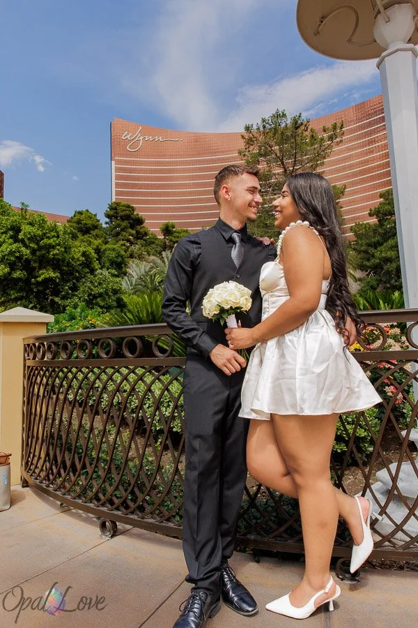 Newlywed couple smiling at each other with Wynn Las Vegas in the background.