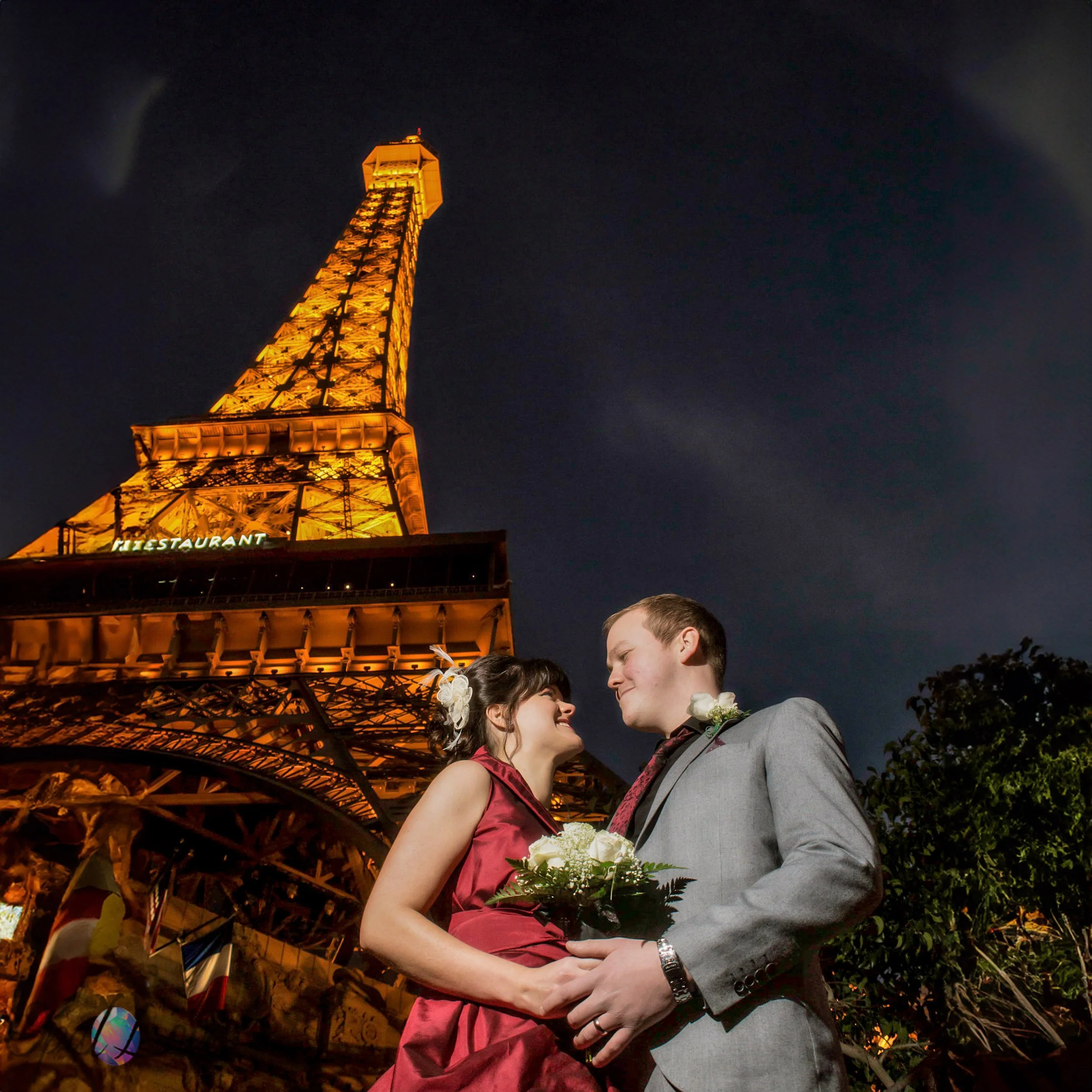 Romantic Las Vegas couple portrait beneath the illuminated Eiffel Tower at Paris Las Vegas, photographed at night by Opal Love Photography.