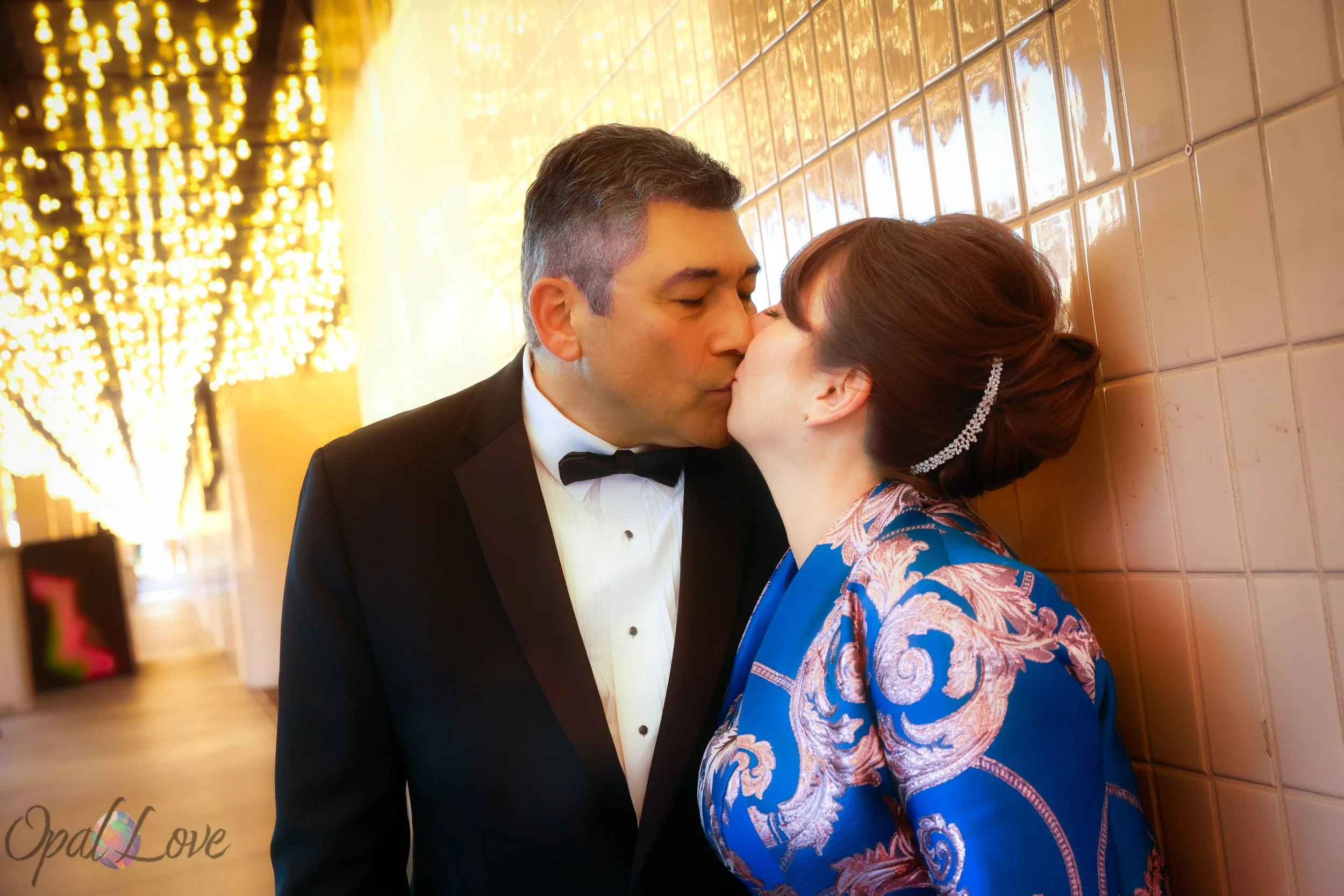 Couple kissing along a mirrored wall with warm bulbs on Fremont Street.