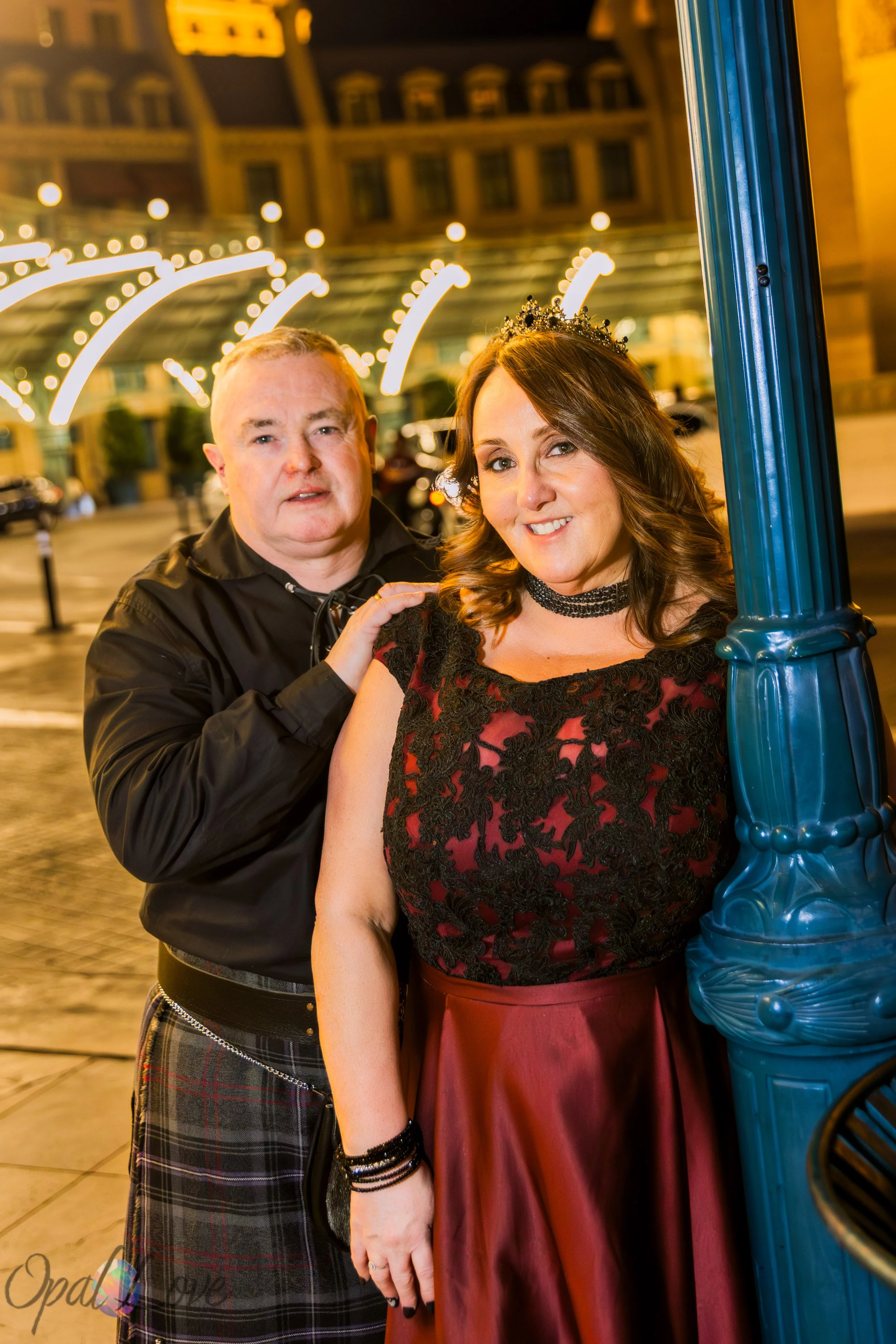 Newlywed couple portrait beside Paris Las Vegas at night with Strip lights in the background.