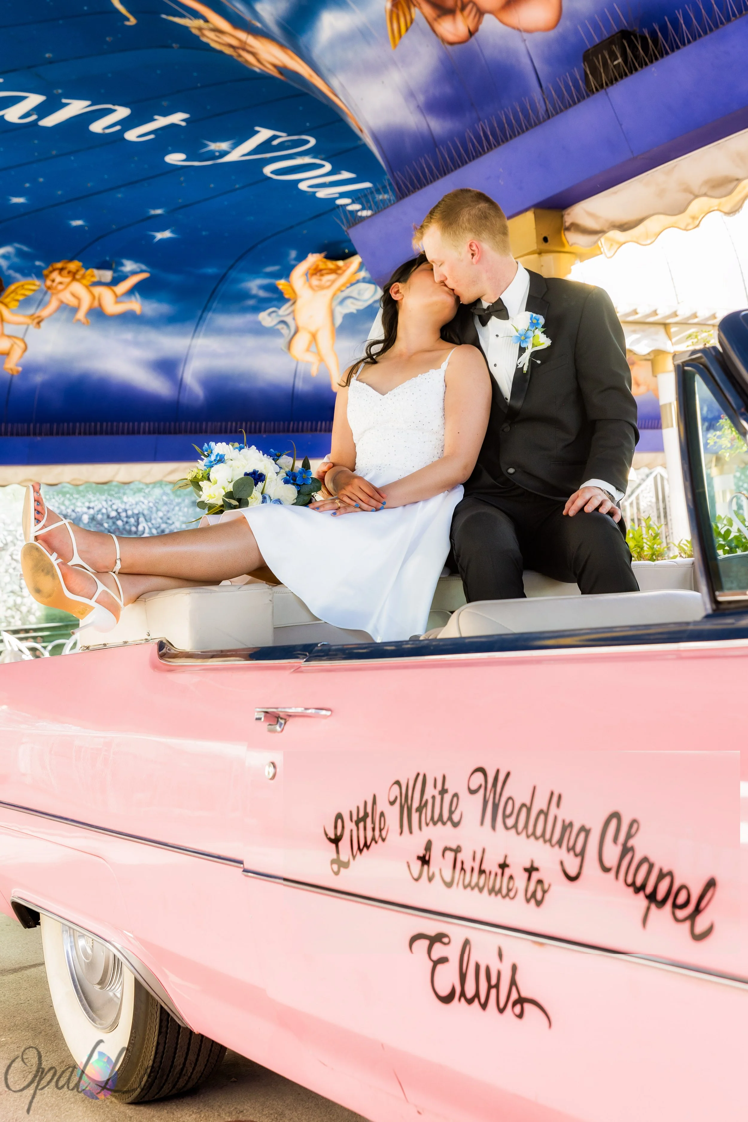 Newlywed couple kissing inside the pink Cadillac at the Little White Wedding Chapel in Las Vegas.