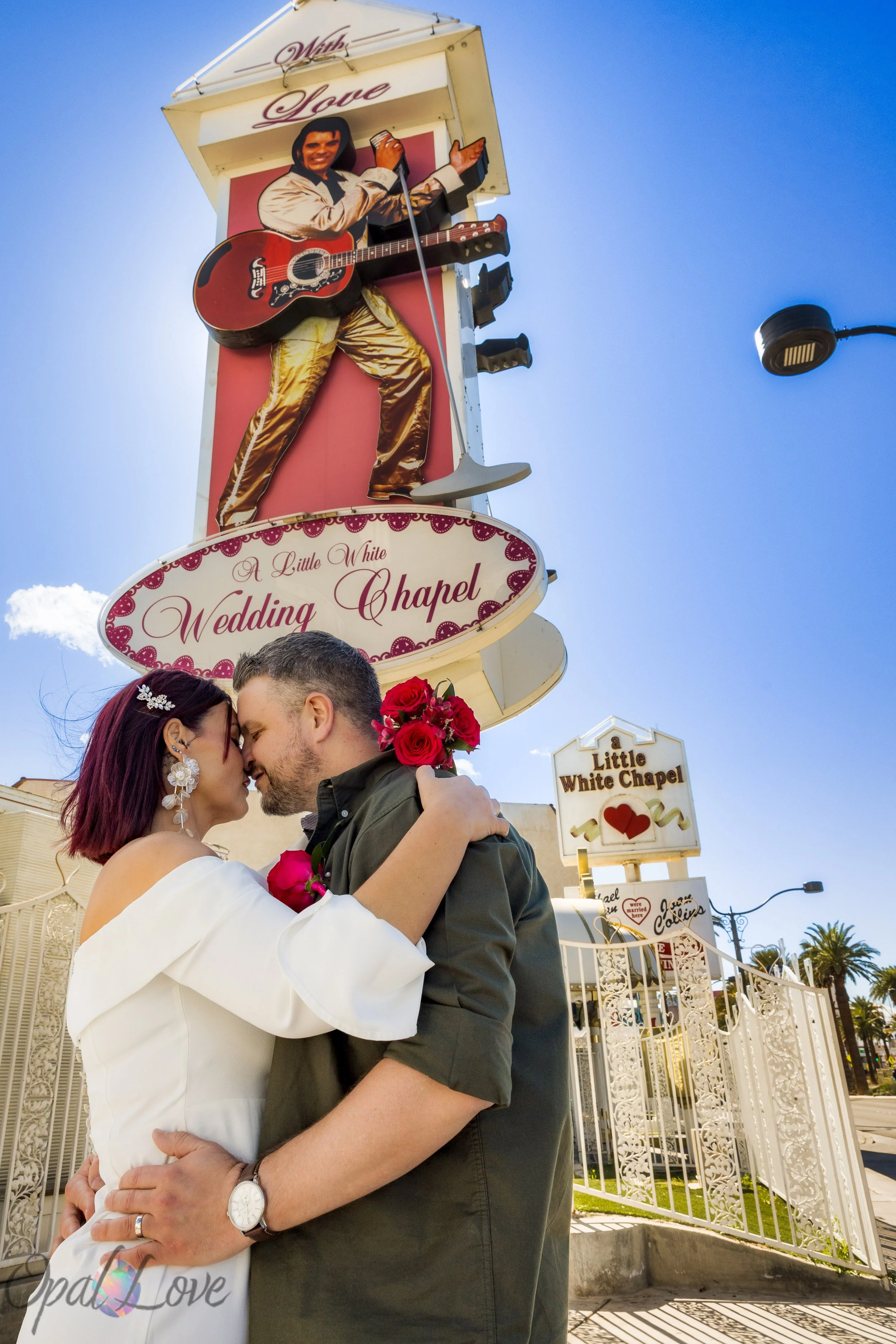 Couple hugging under the iconic Elvis sign at A Little White Wedding Chapel in Las Vegas.