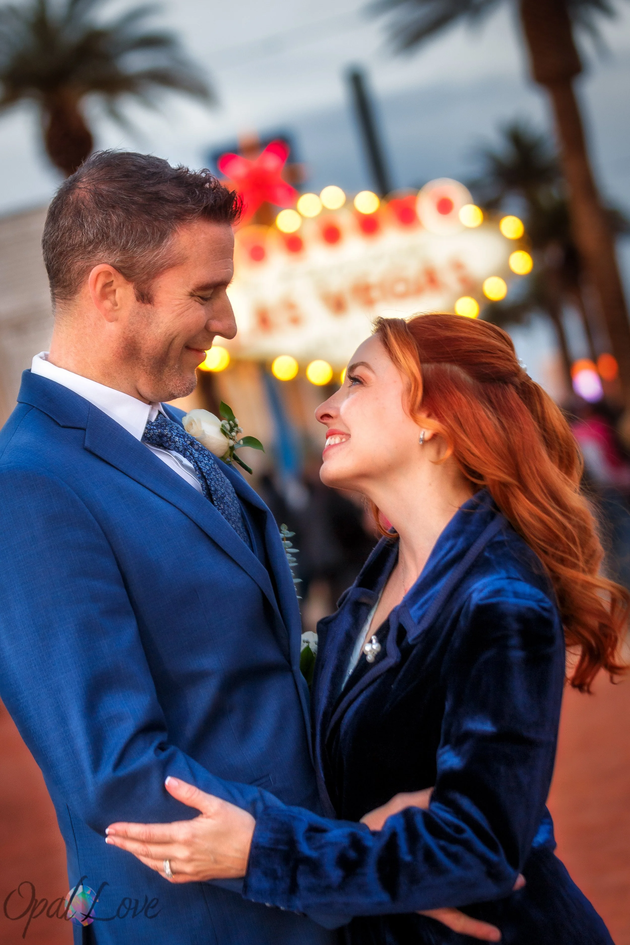 Couple staring at each other's eyes in front of the welcome to Las Vegas line on a Las Vegas photo tour