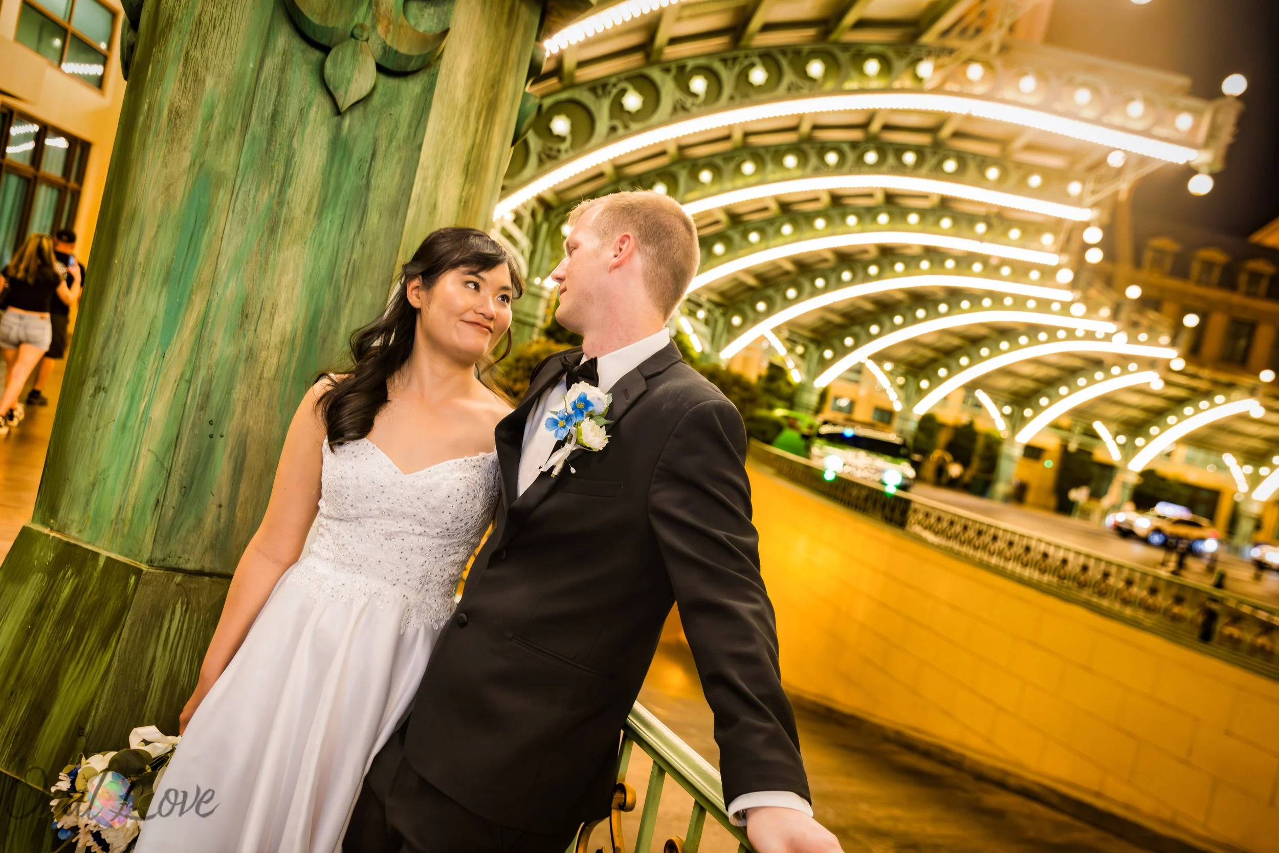 Couple posing under the illuminated entrance at Paris Las Vegas during their wedding photo tour.