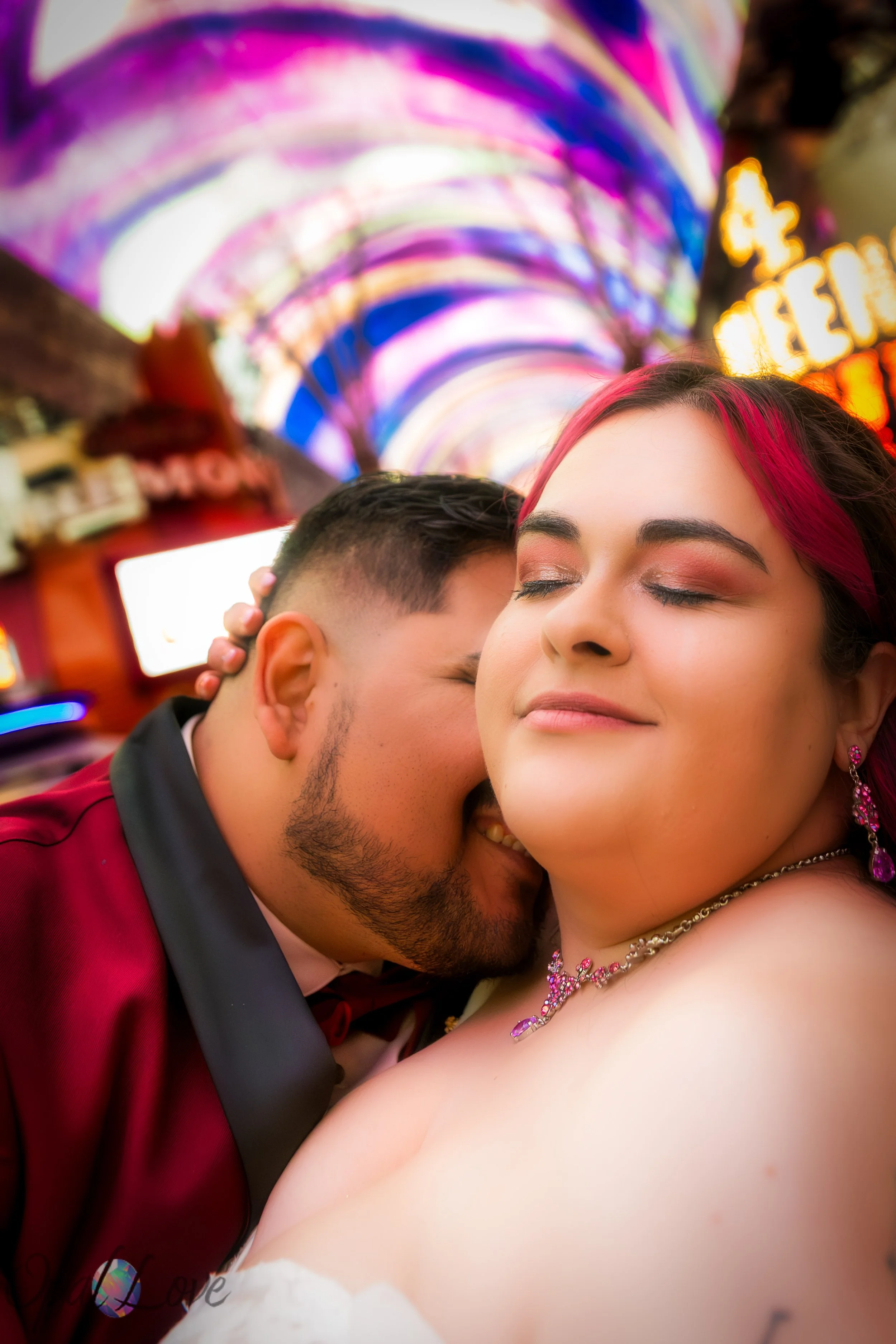 Couple cuddling under the colorful Fremont Street canopy lights.