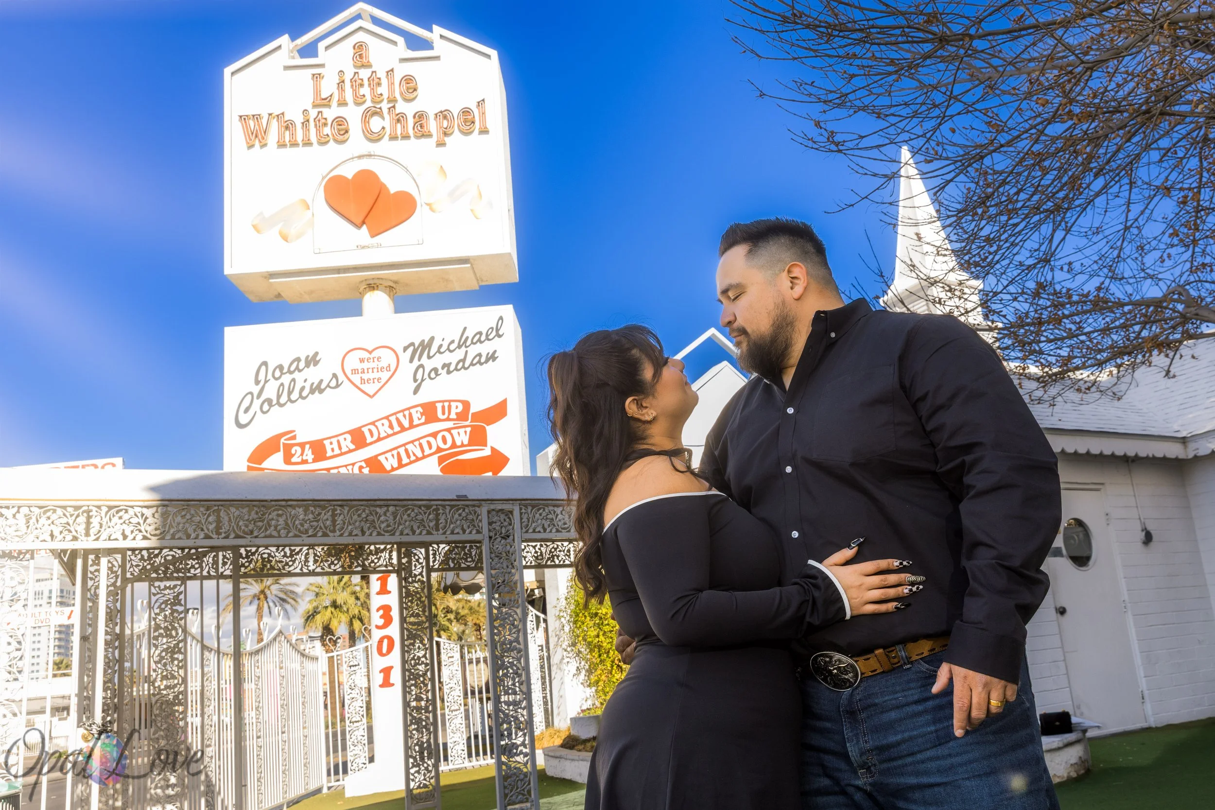 Newlyweds standing together in front of A Little White Wedding Chapel sign in Las Vegas.