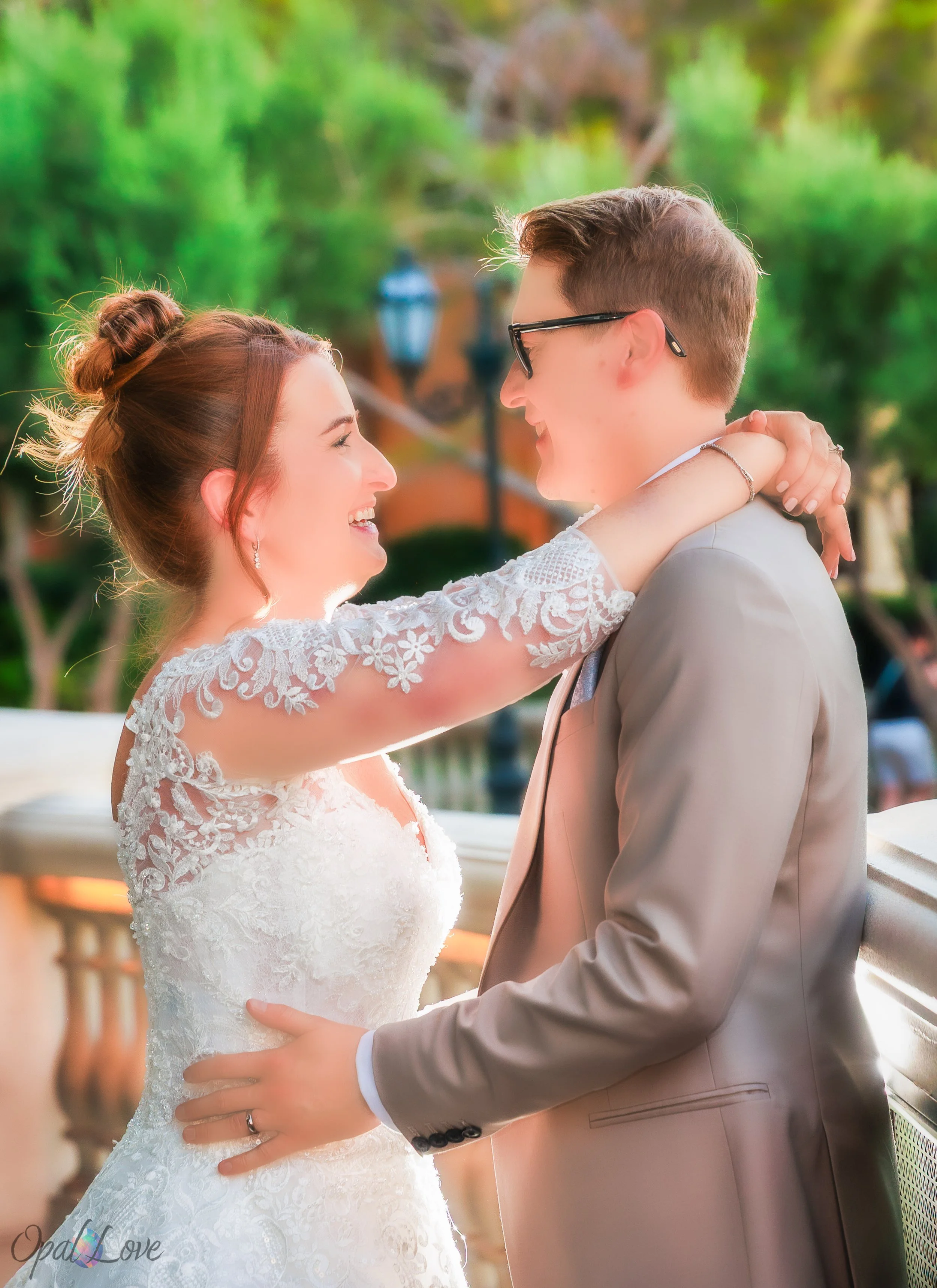 "Bride smiling at groom with arms around his shoulders at Bellagio gardens during their intimate wedding."