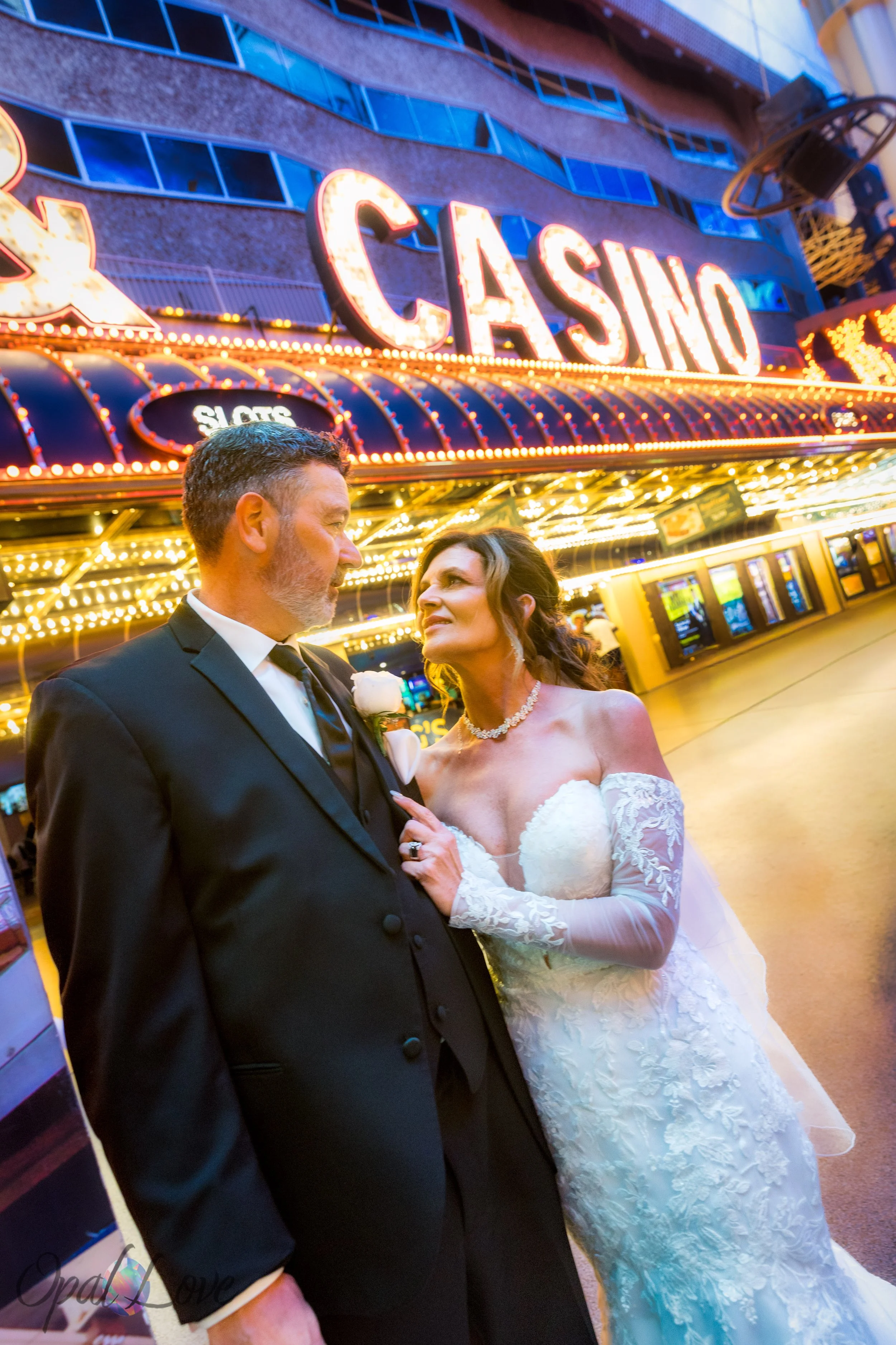 Bride and groom smiling together under golden casino lights on Fremont Street.