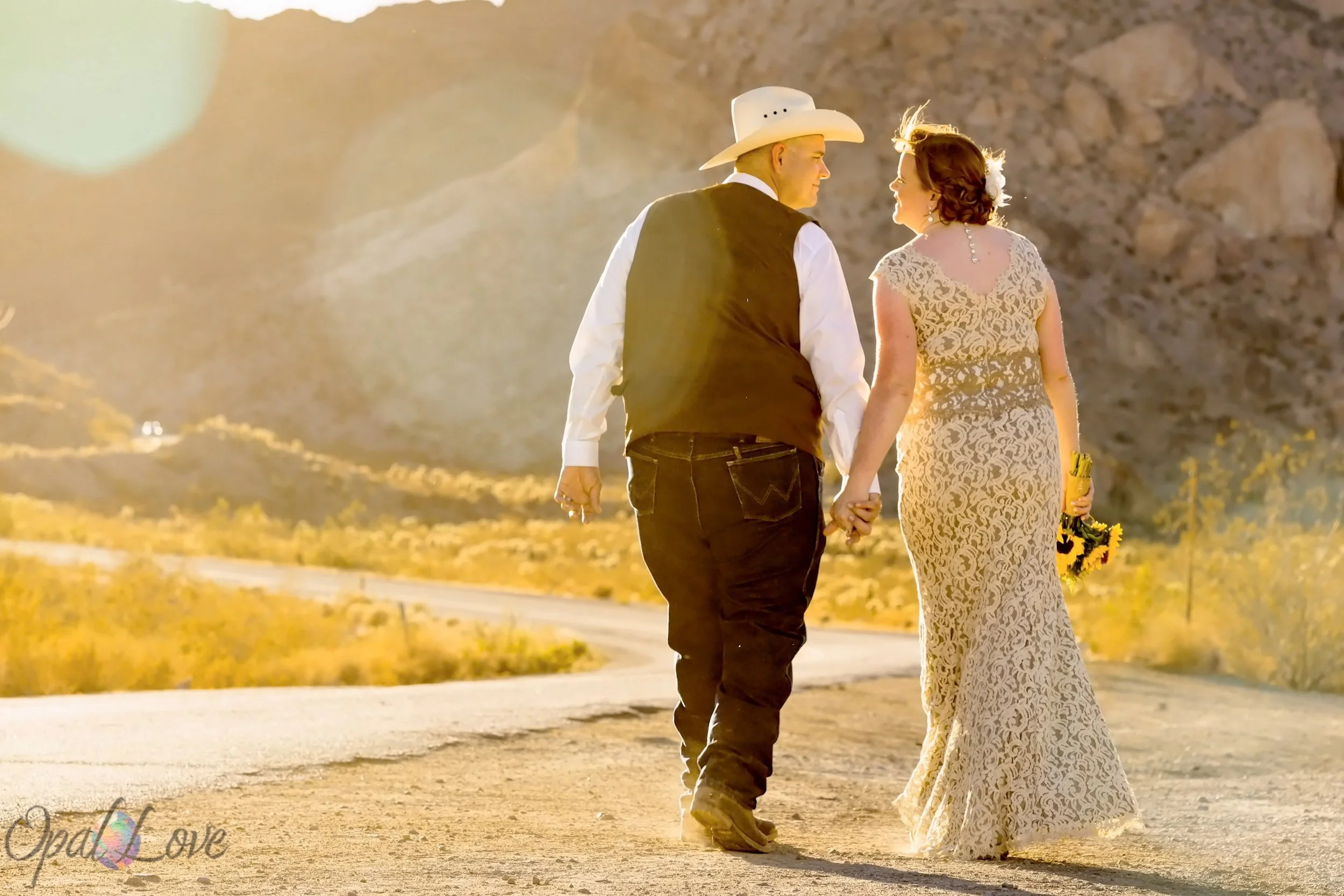 Newlyweds walk hand in hand through the sunlit Nevada desert