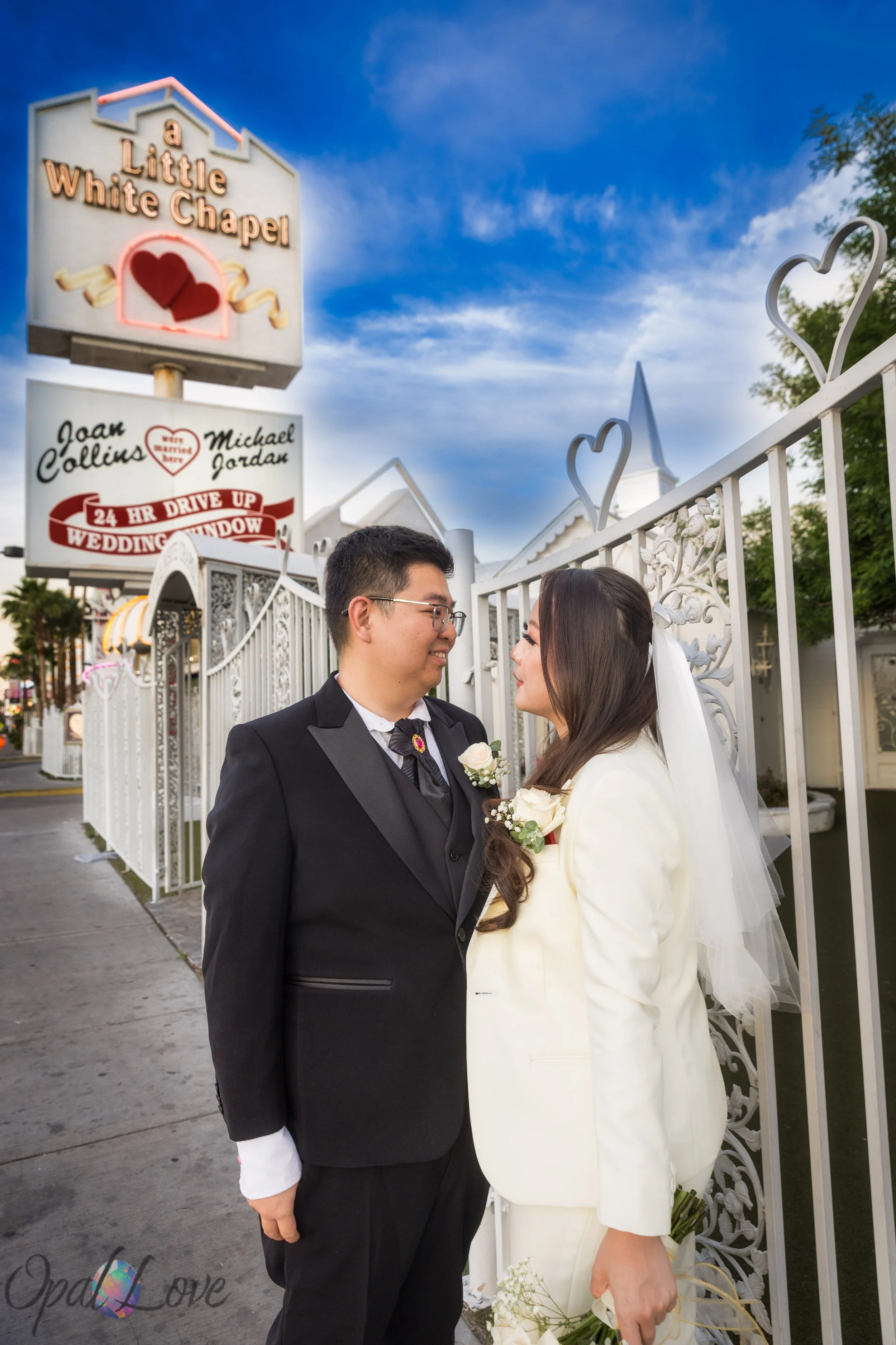 Couple standing together outside Little White Wedding Chapel sign at sunset