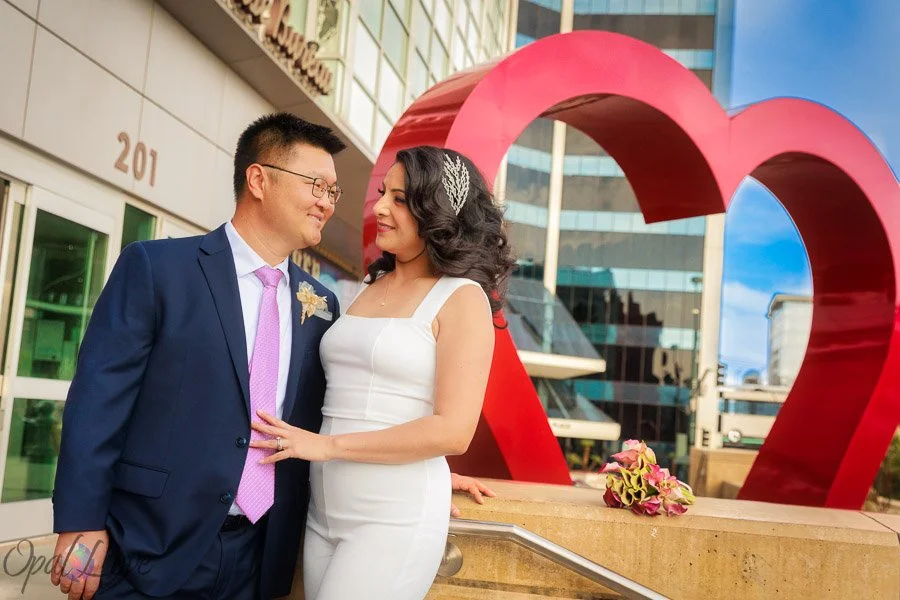 Newlywed couple posing beside the red heart sculpture outside the Las Vegas courthouse.
