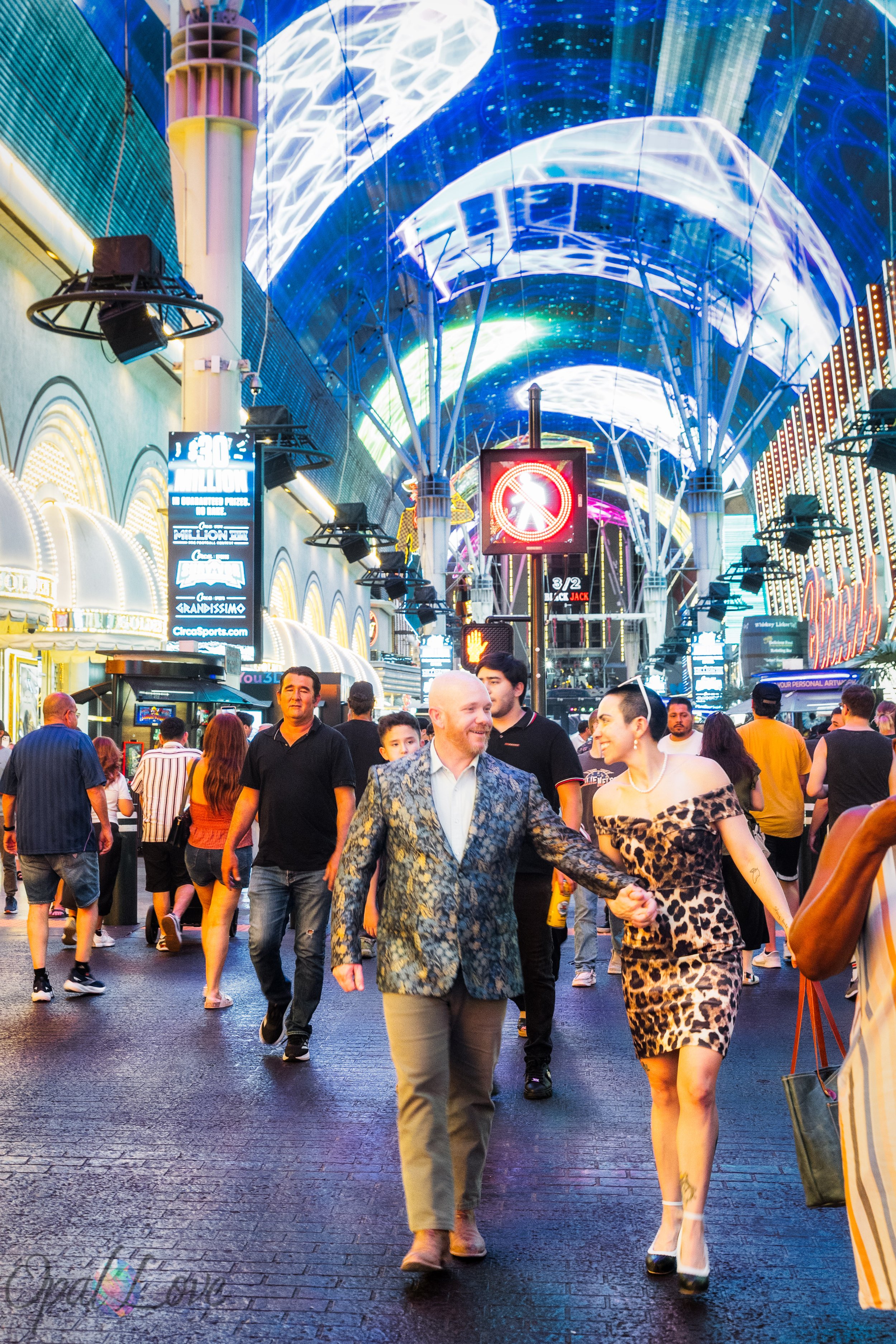 Maddie and Ashley walking hand in hand beneath the illuminated Fremont Street Experience canopy during their Las Vegas photo tour.