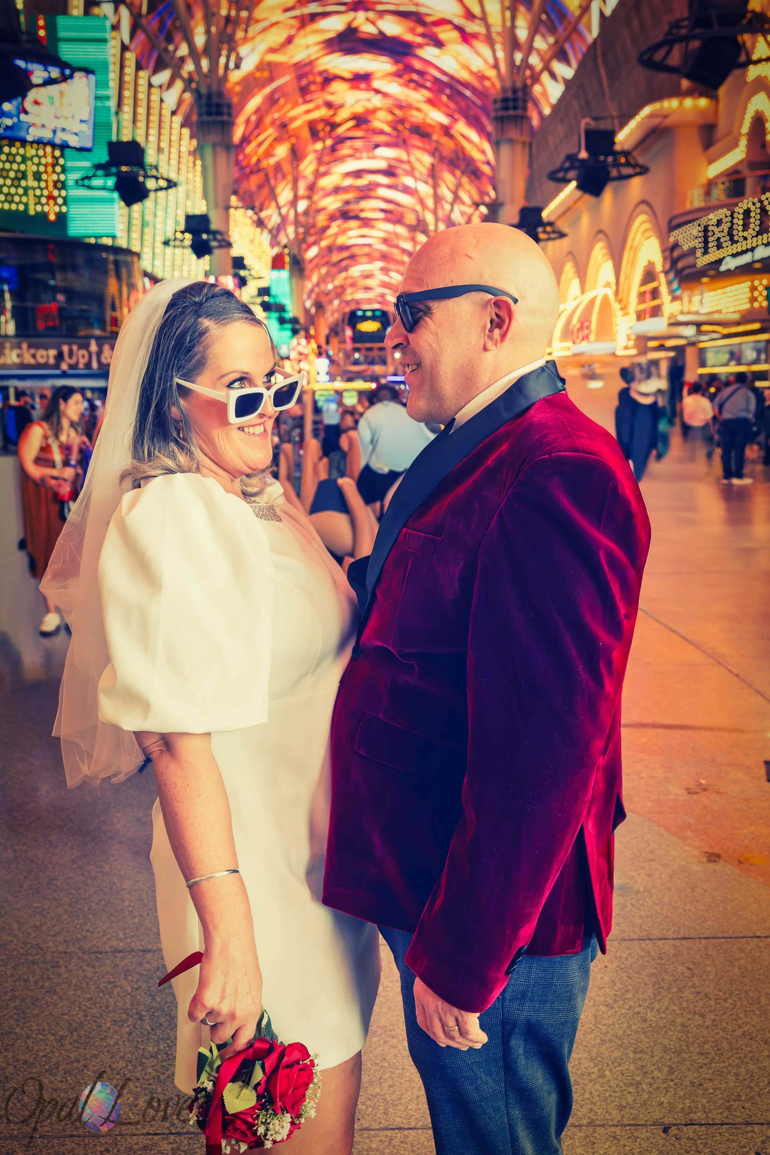 Couple laughing together under the colorful canopy lights of Fremont Street during their Las Vegas elopement captured by Opal Love Photography.