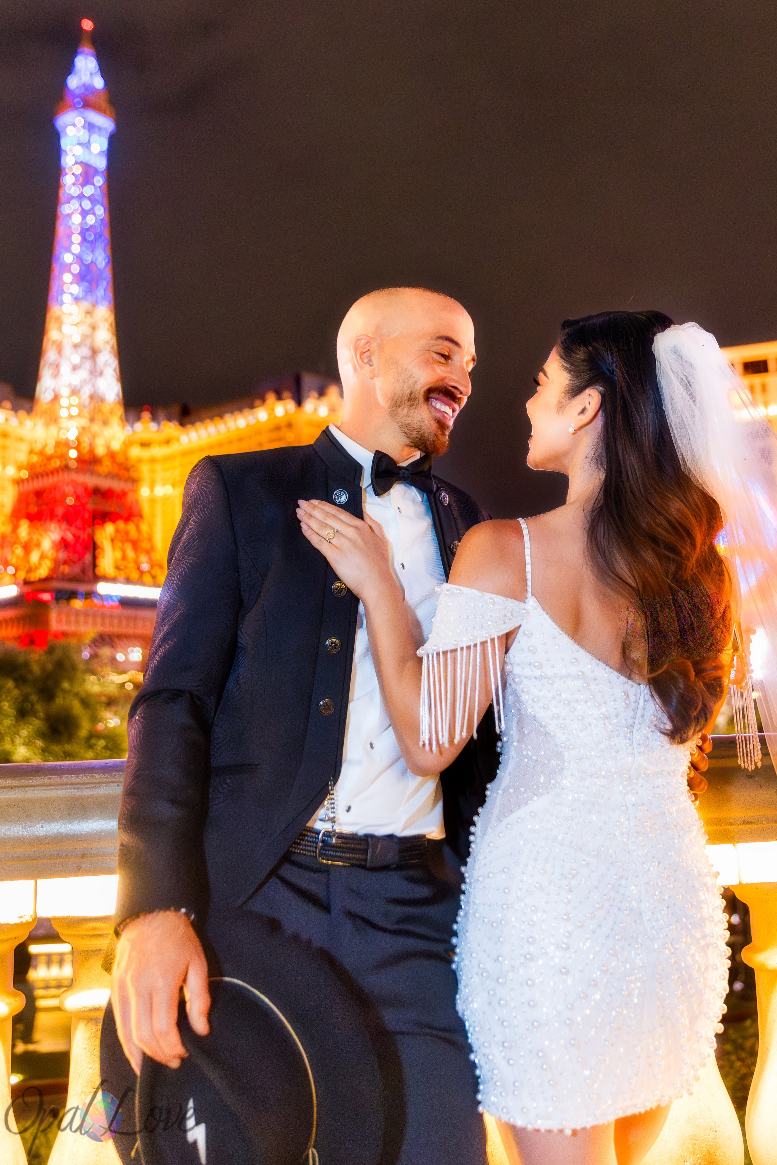 Bride and groom standing along Bellagio railing with Las Vegas Strip lights behind them