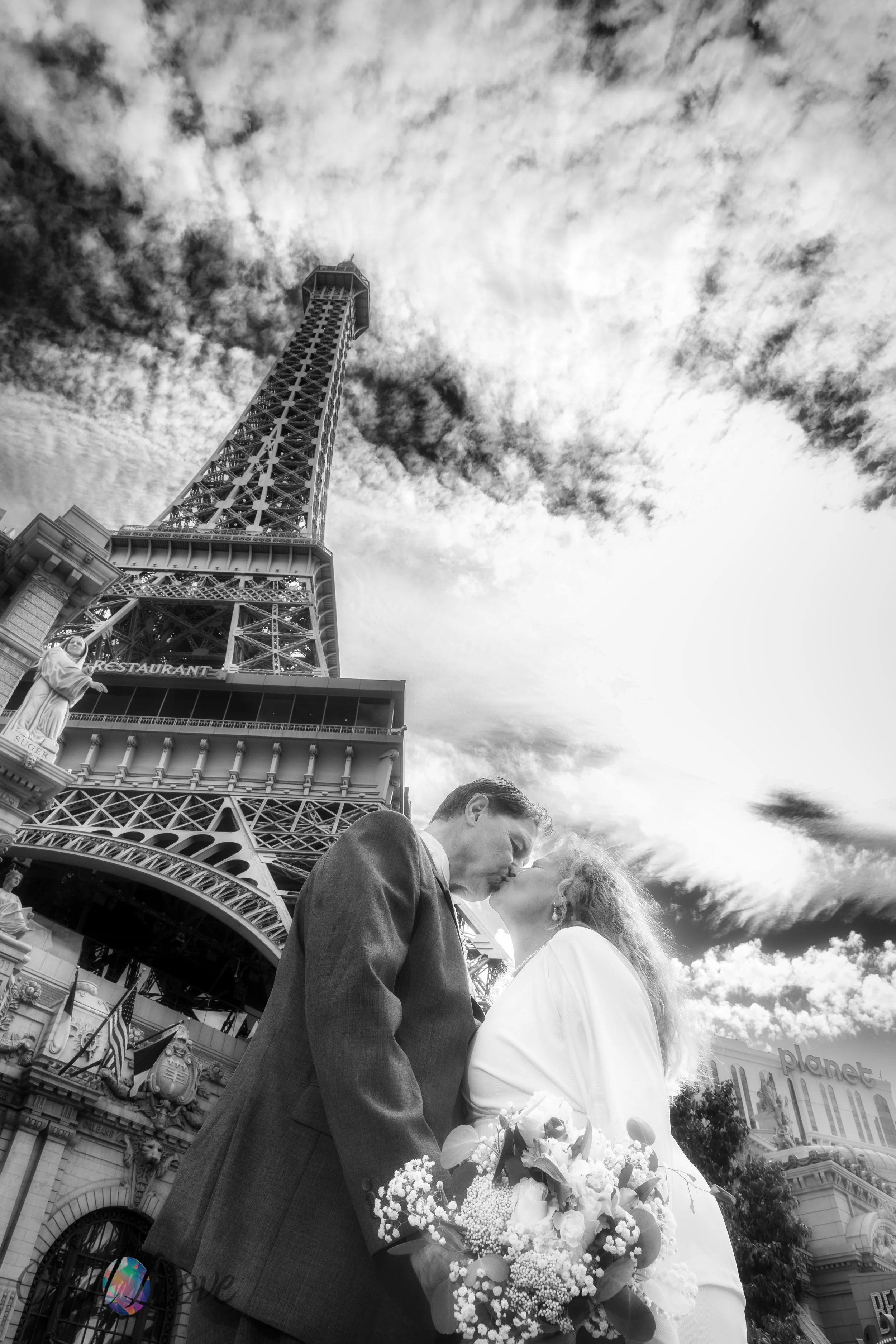 Black and white photo of couple kissing beneath Eiffel Tower after Vegas elopement