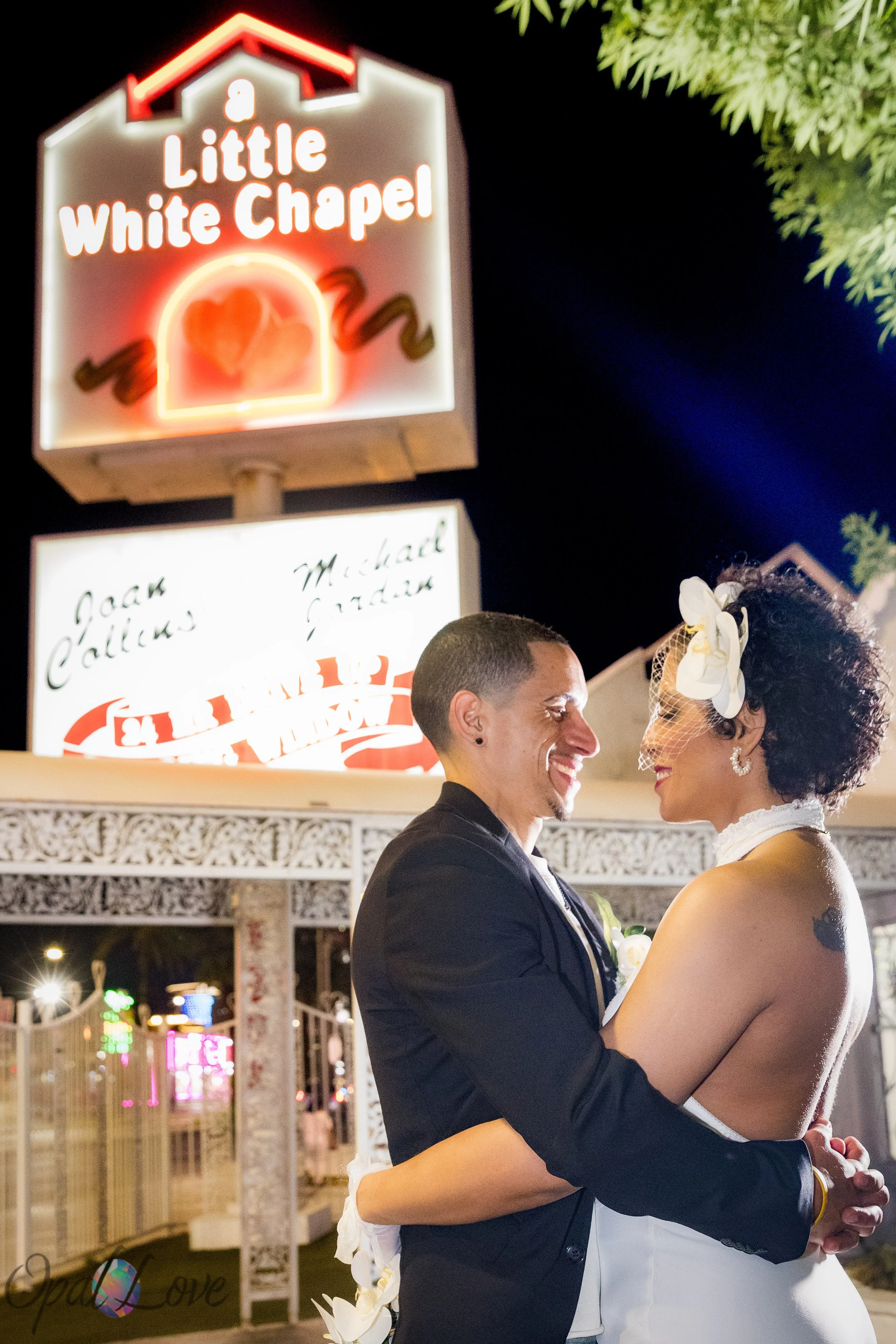 Couple embracing in front of the Little White Wedding Chapel sign during their Las Vegas wedding.