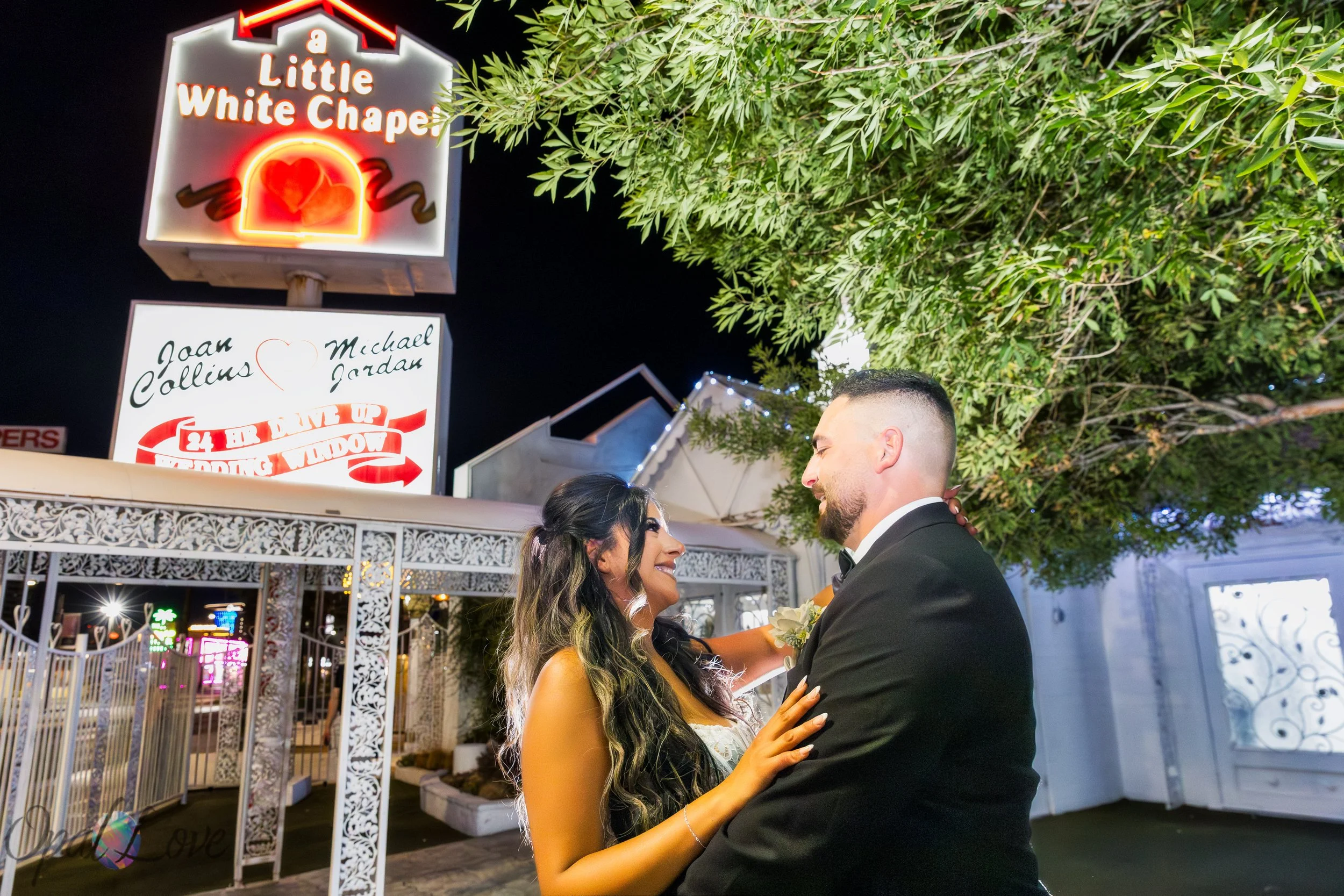Alysha and Justin together beneath the illuminated Little White Wedding Chapel sign during their nighttime Las Vegas wedding portraits.