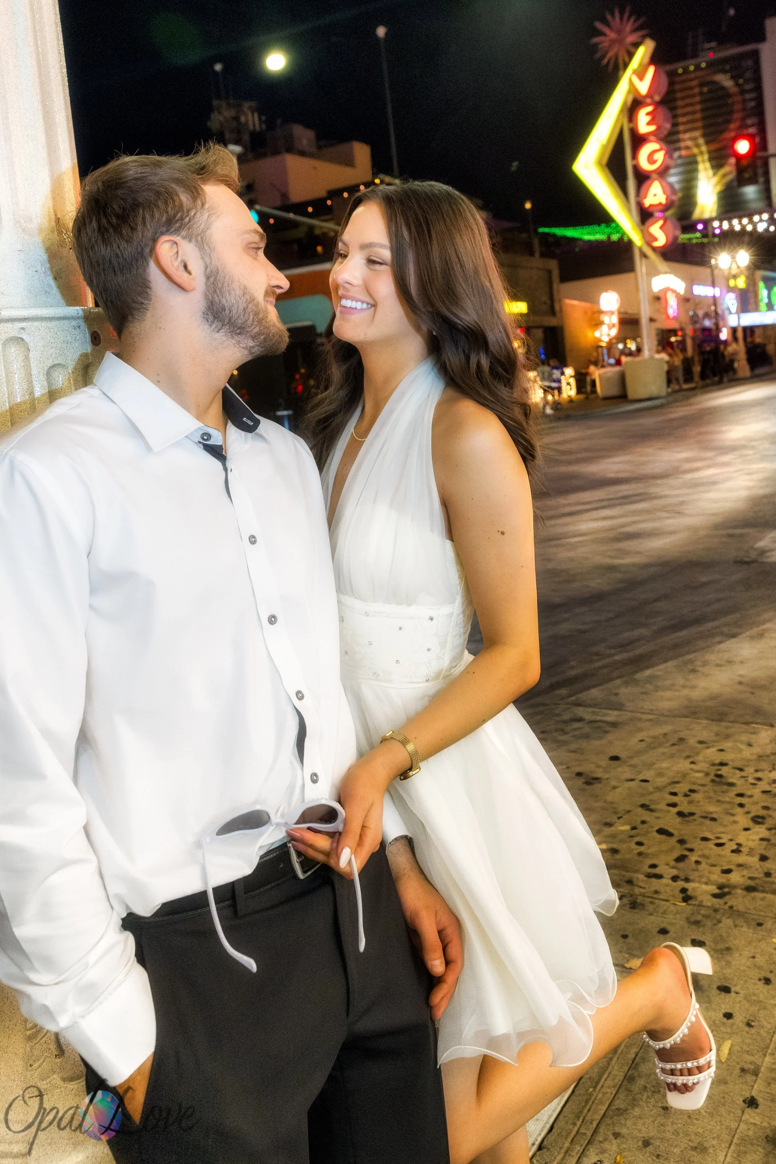 Couple smiling at each other on Fremont Street with classic Vegas neon signs in the background.