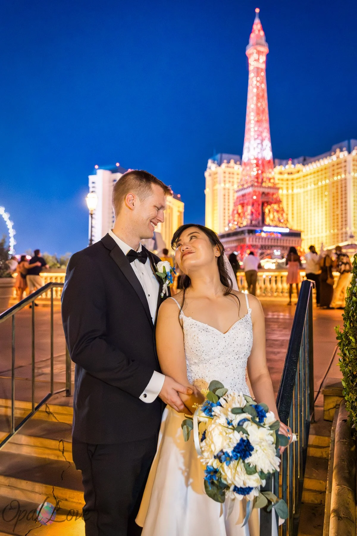 Newlyweds smile with the Bellagio fountains and Eiffel Tower behind them