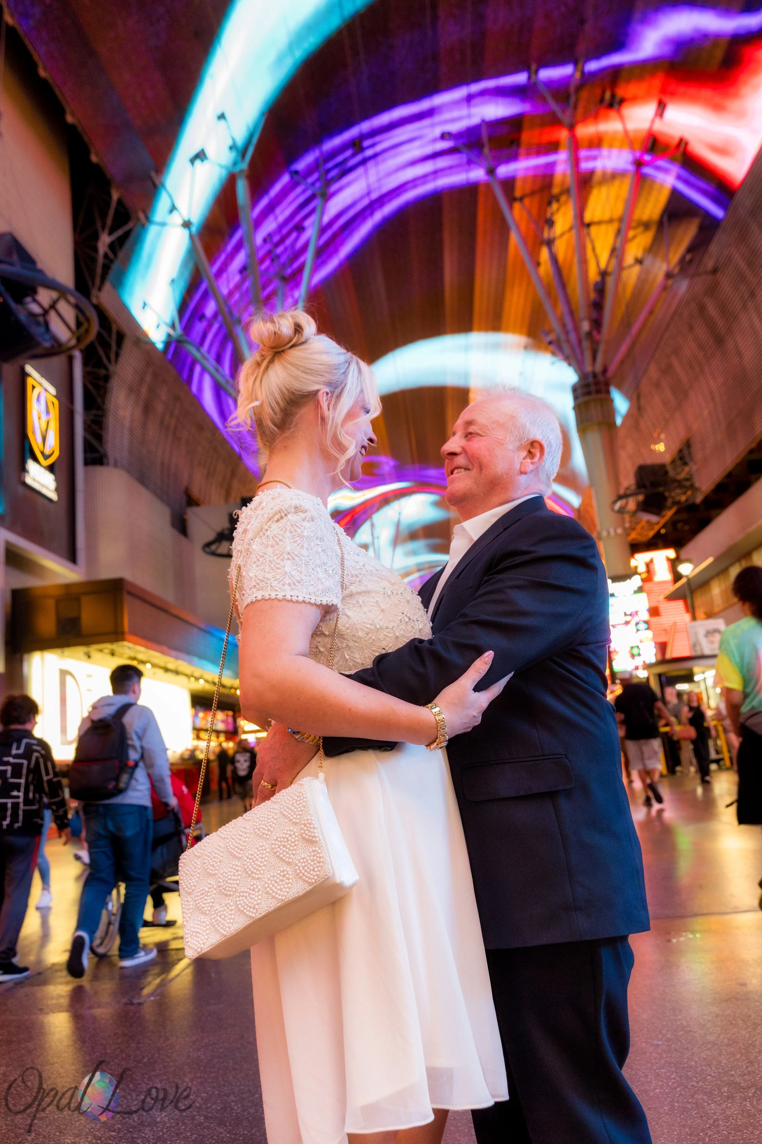 Bride and groom embracing beneath the colorful Fremont Street Experience canopy.