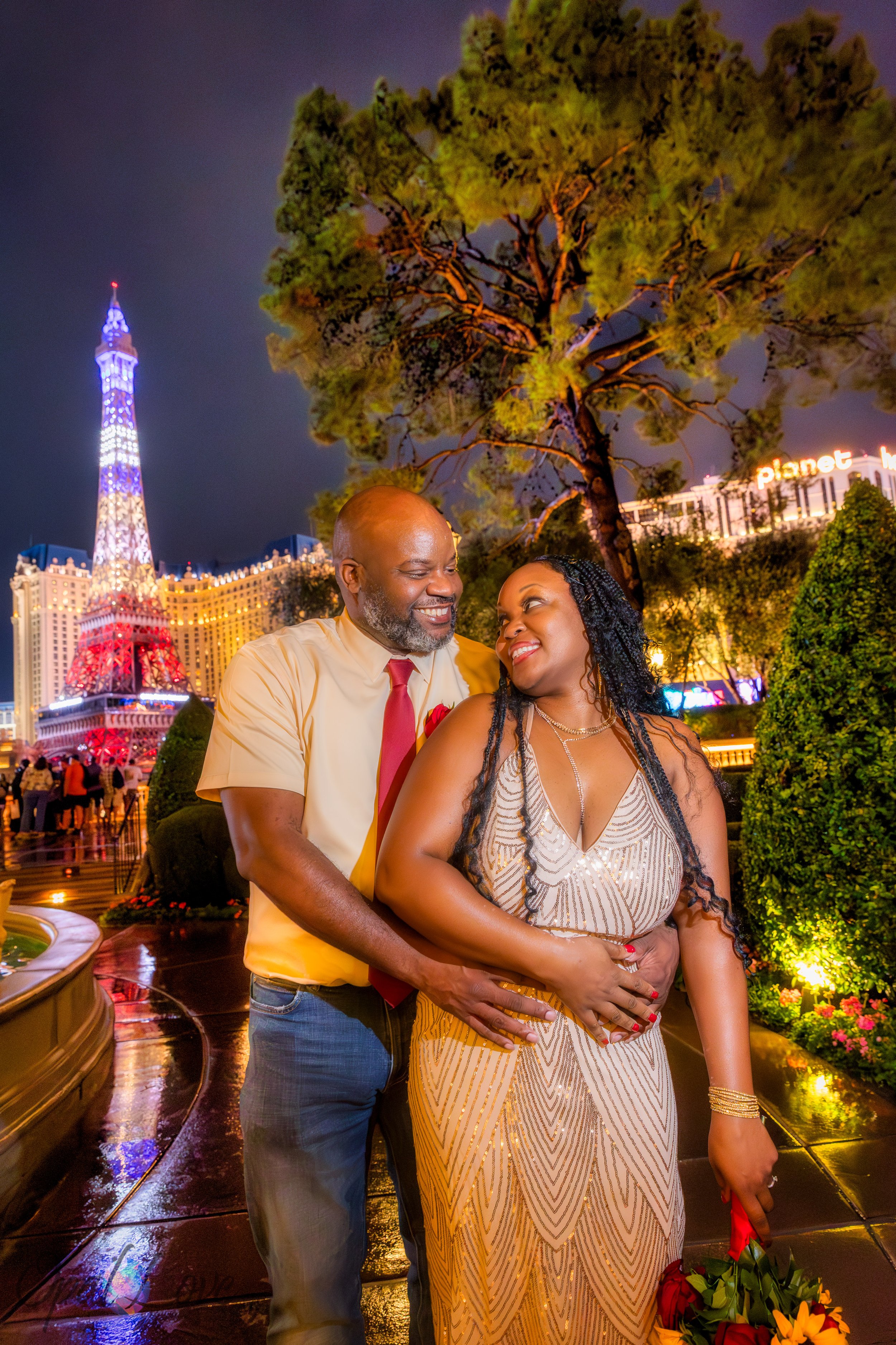 Couple standing together beneath the Eiffel Tower lights at Paris Las Vegas