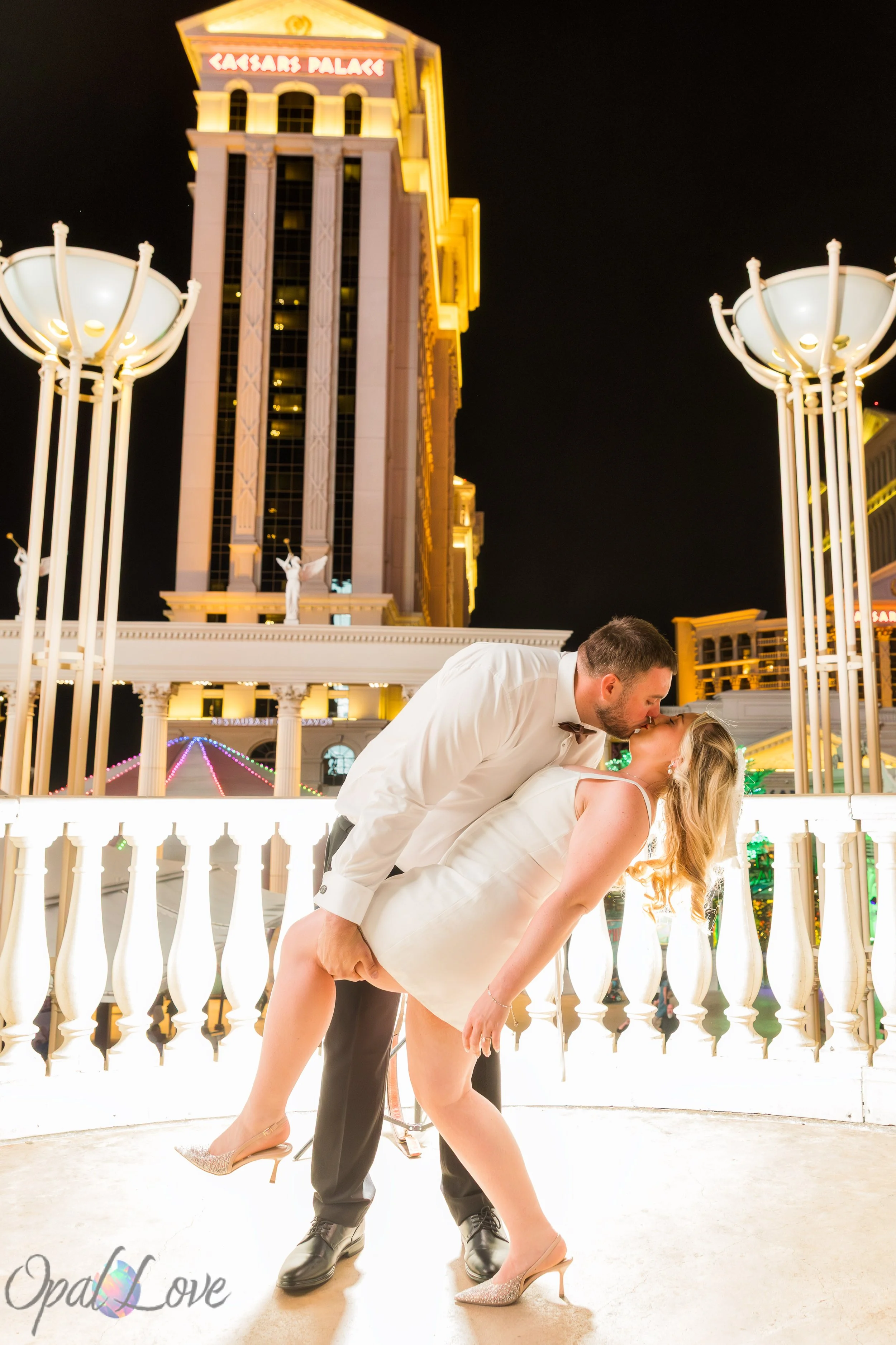 Romantic dip kiss portrait of a newlywed couple at Caesars Palace at night.