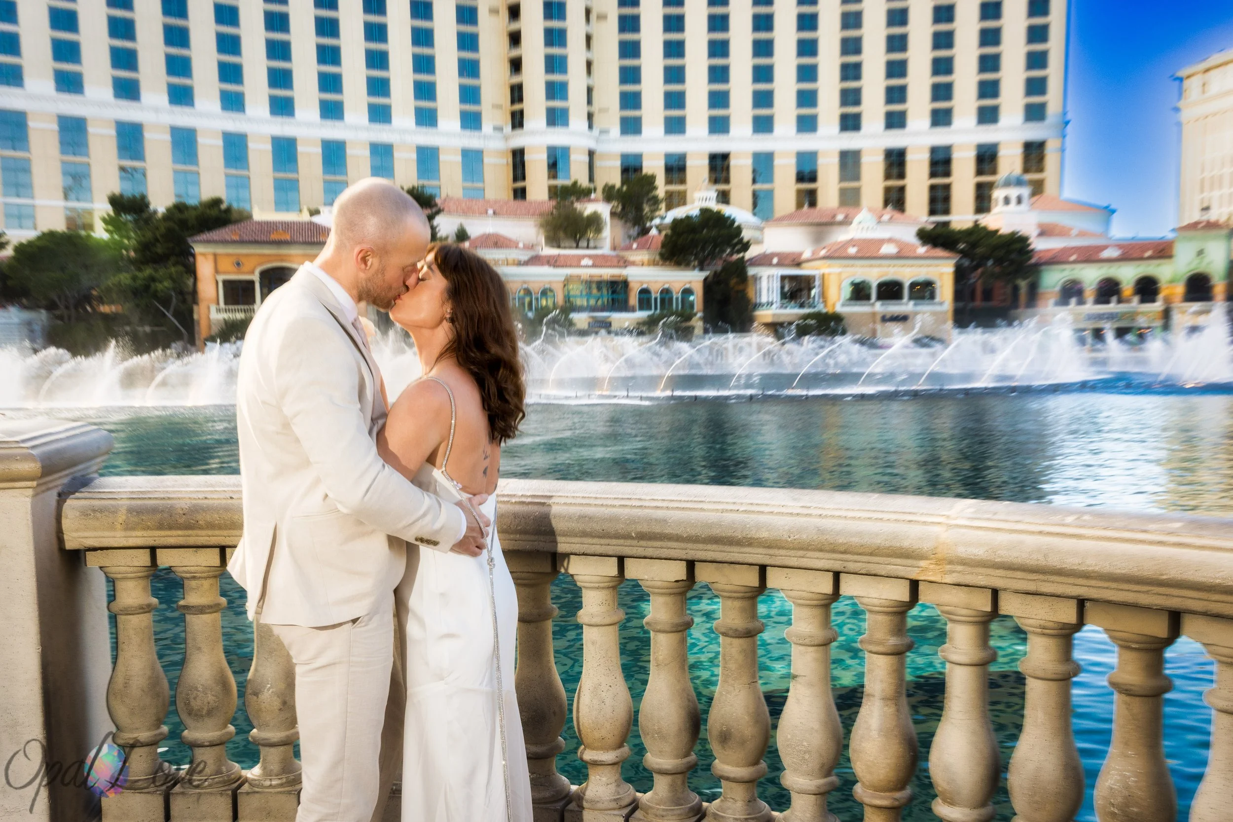 Newlyweds kissing in front of the Bellagio fountains on the Las Vegas Strip.