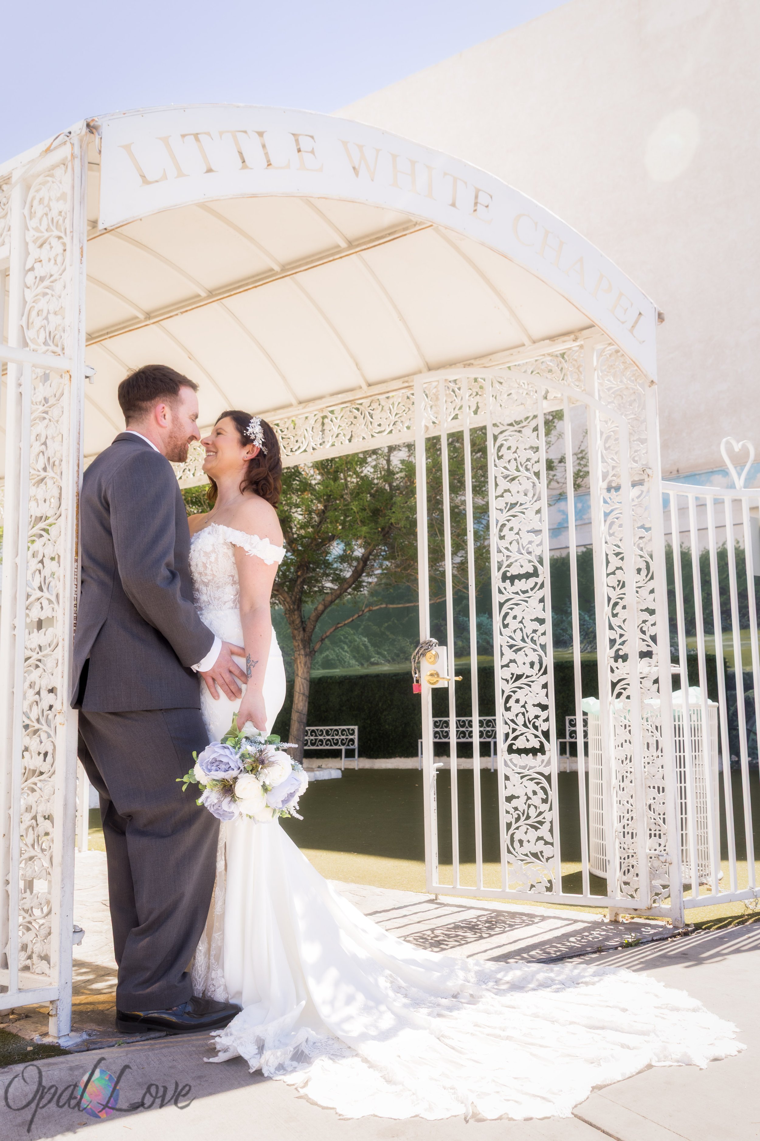 Couple standing together under the white entrance gate at Little White Chapel in Las Vegas.
