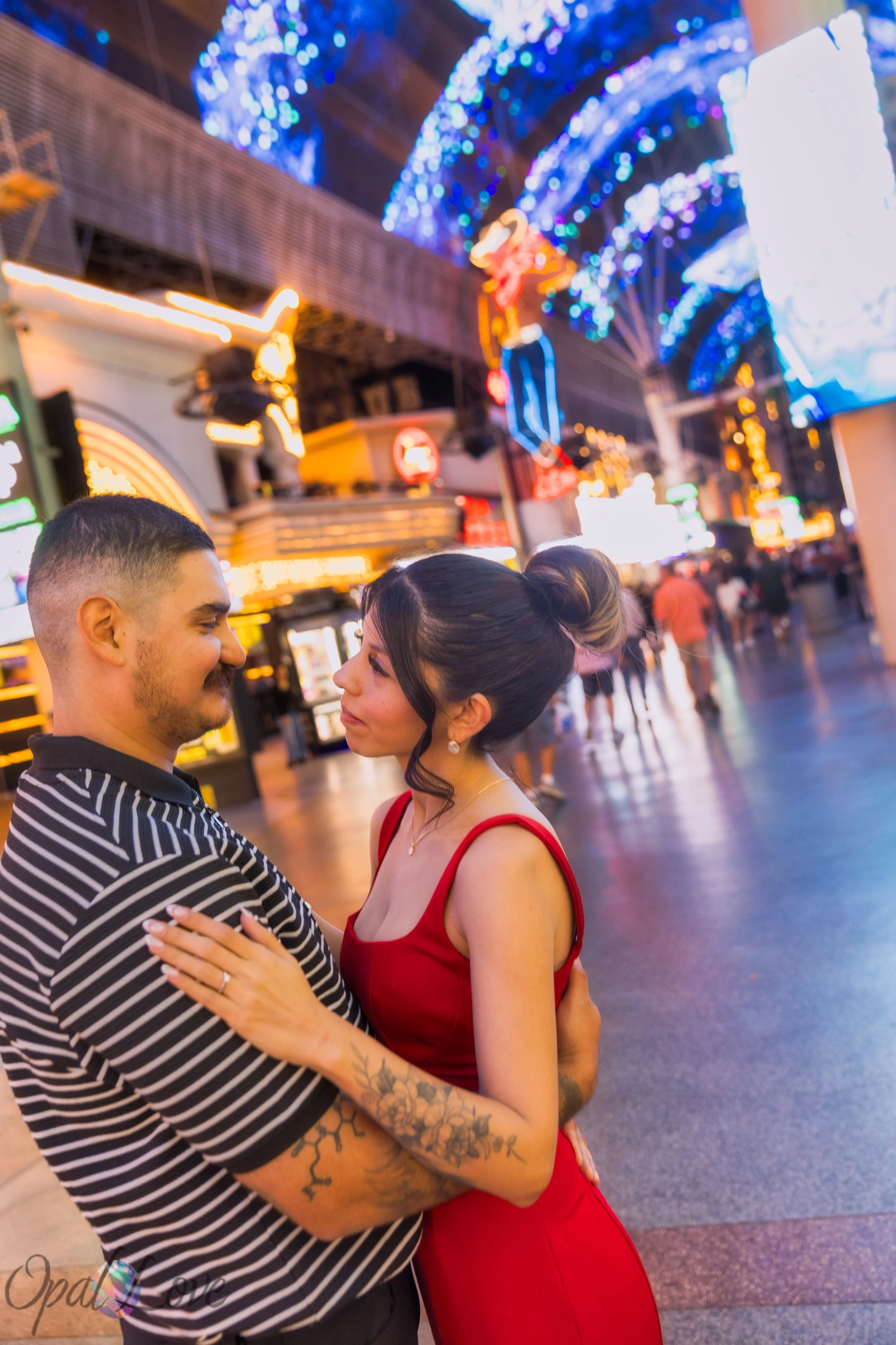 Couple standing close together on Fremont Street with colorful lights in background