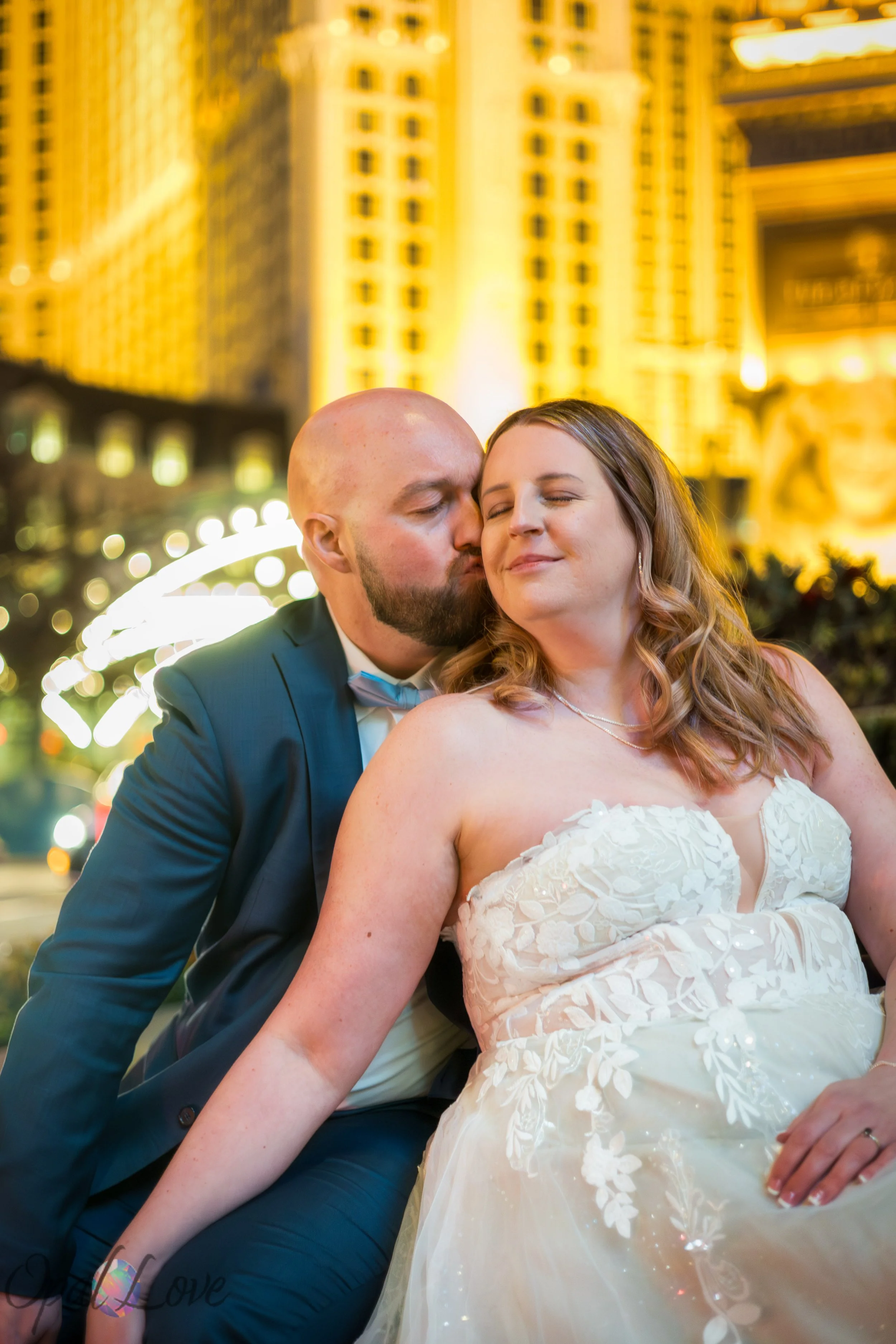 Newlyweds embracing with the illuminated Eiffel Tower at Paris Las Vegas in the background.