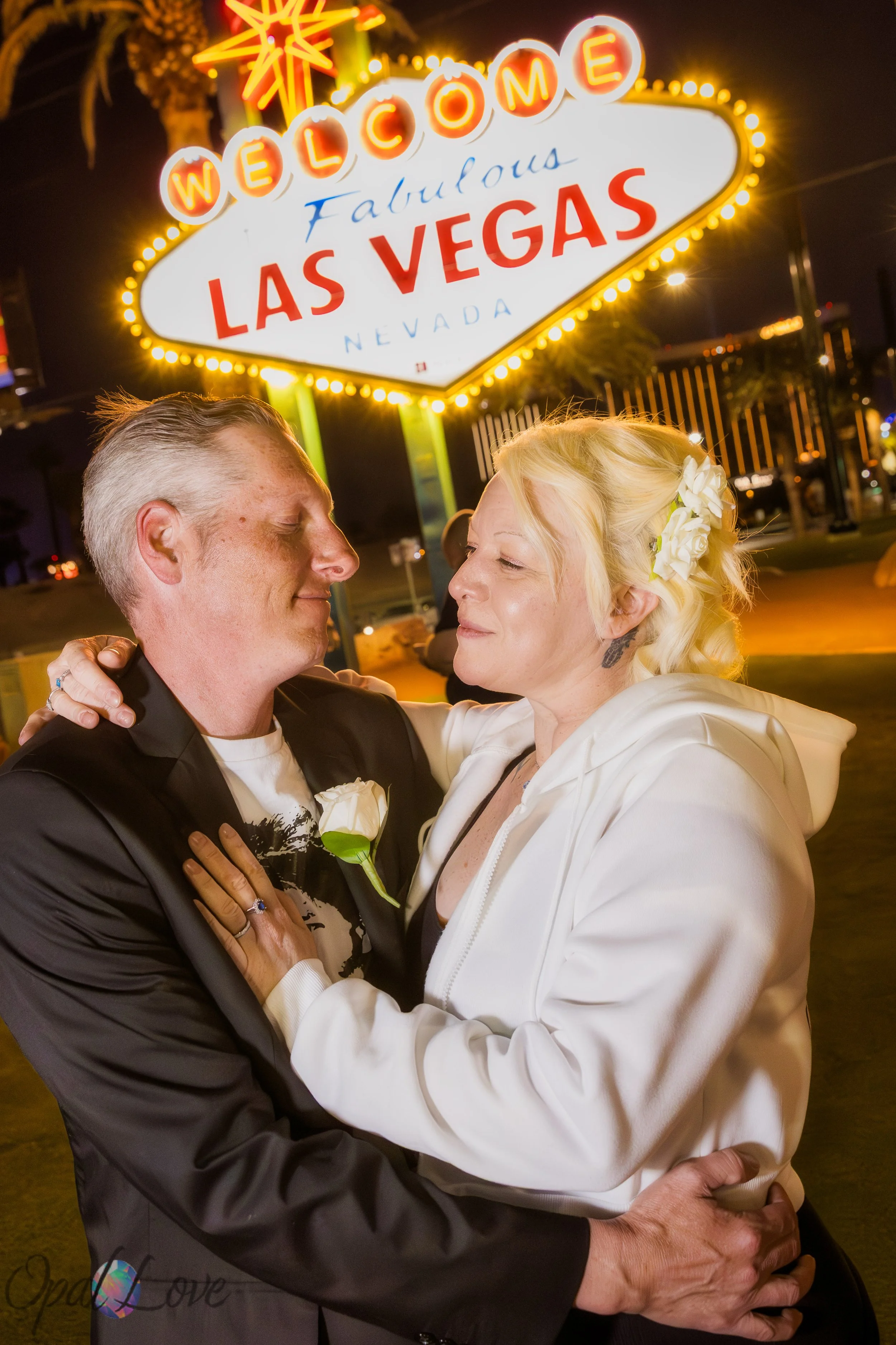 Couple embracing at the Welcome to Las Vegas Sign at night after their elopement