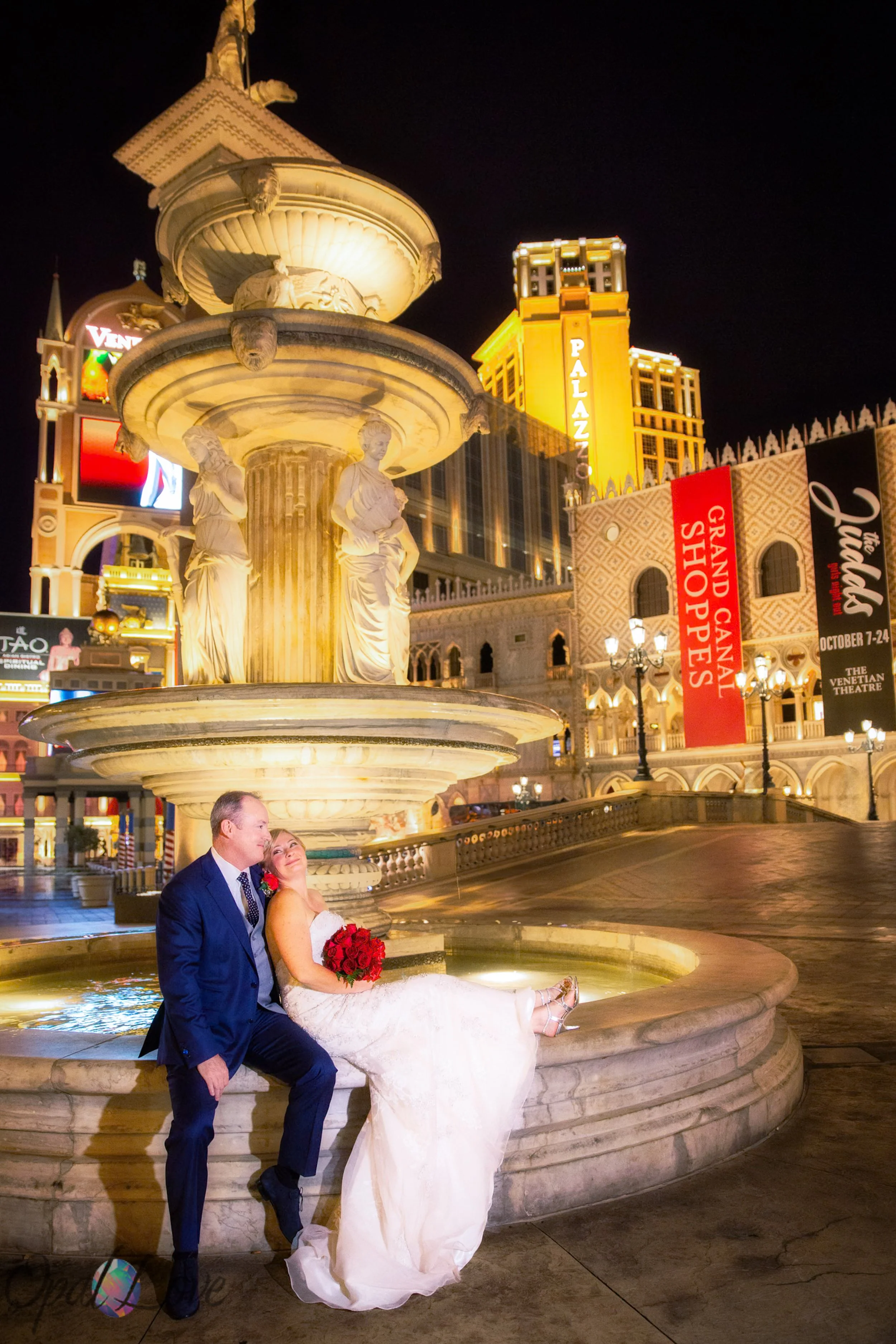Wedding couple beside an illuminated fountain at The Venetian in the North Strip walking zone.