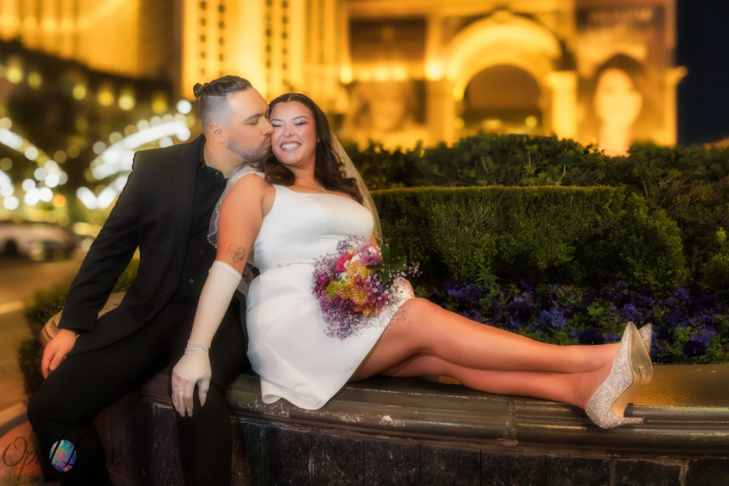 Couple sharing a kiss with the Paris Las Vegas Eiffel Tower illuminated behind them.