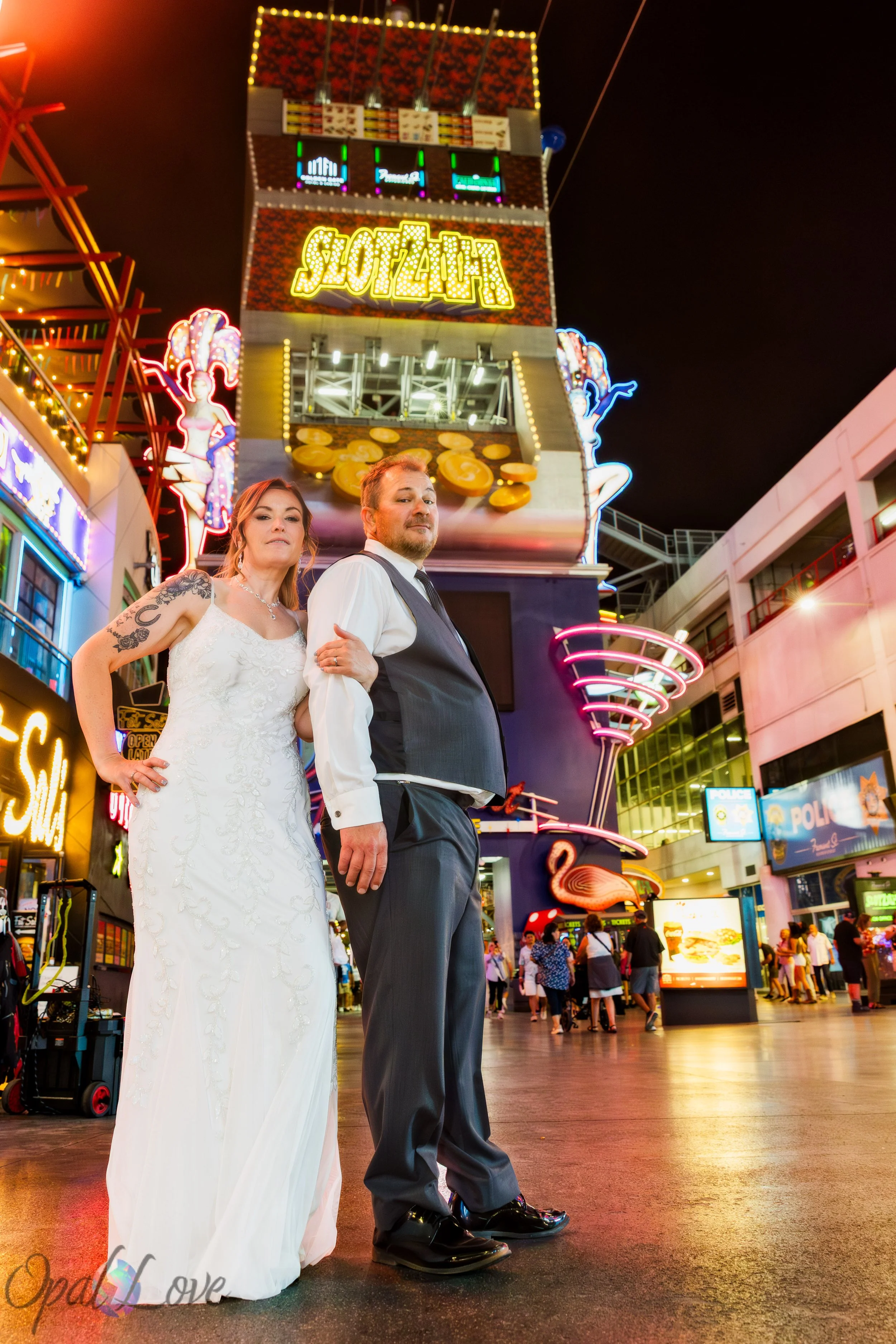 Bride and groom posing beneath the SlotZilla attraction during their Fremont Street wedding photo tour.