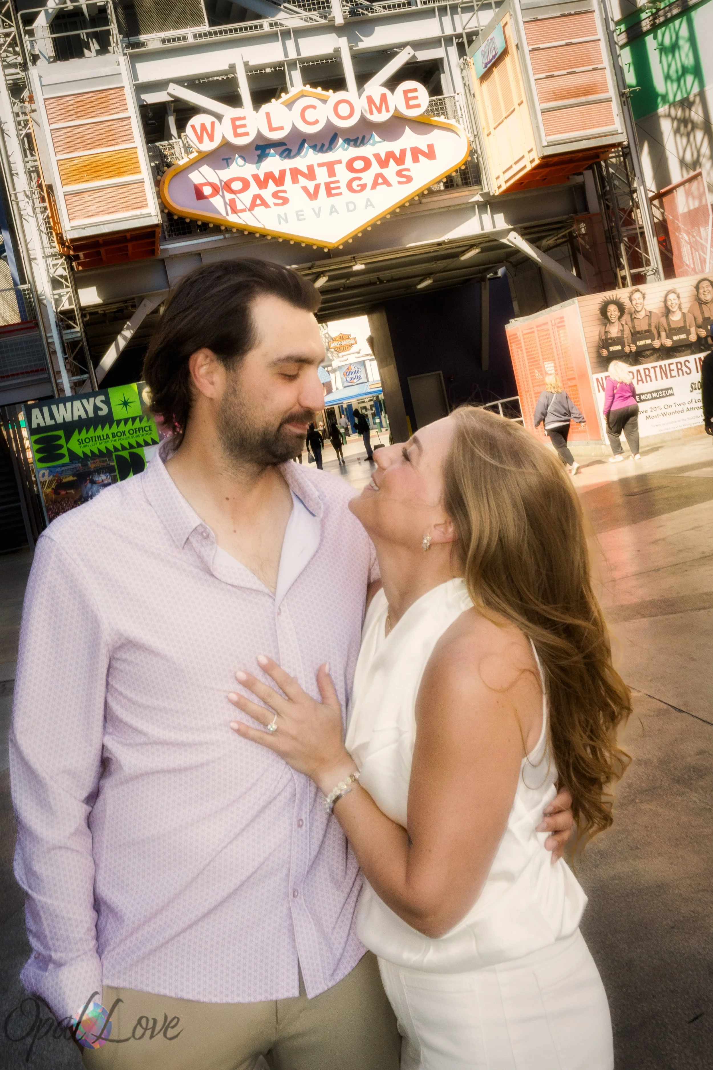Engaged couple smiling together under the Welcome to Downtown Las Vegas sign on Fremont Street.