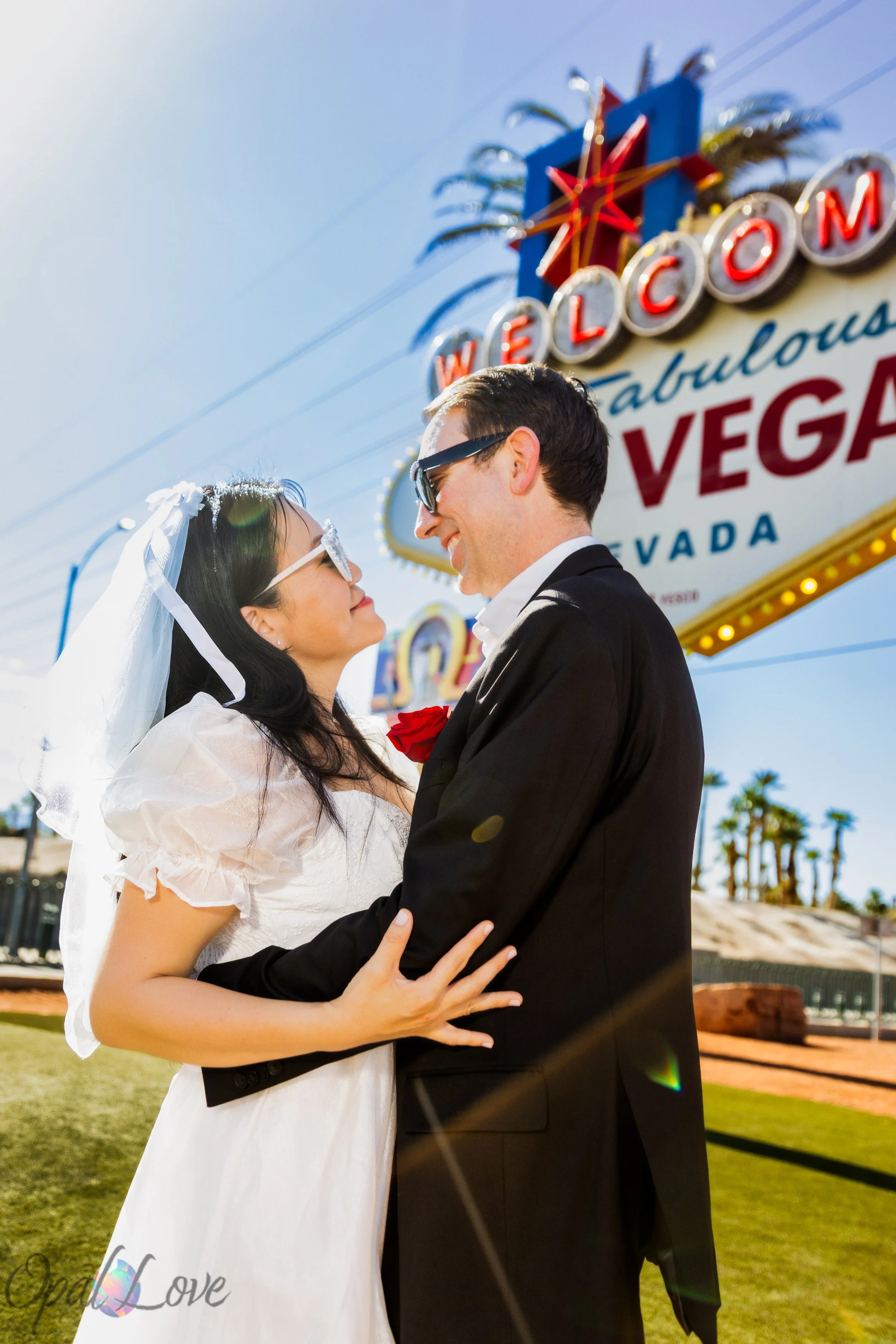 Newly married couple embracing beneath the Welcome to Las Vegas Sign on their Las Vegas wedding day