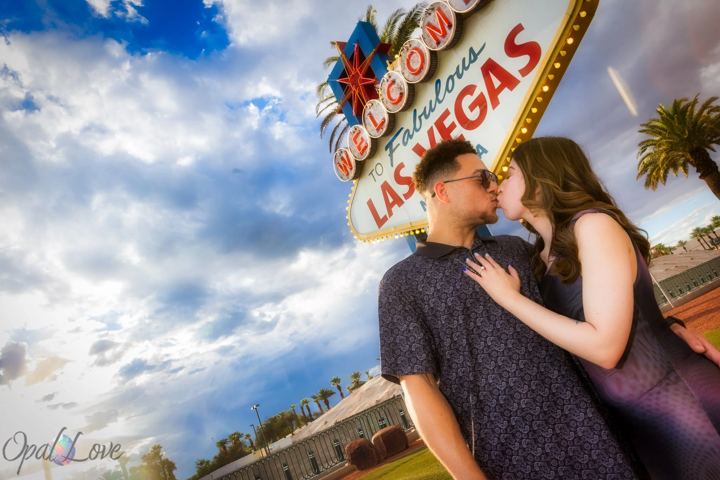 Newly engaged couple celebrating their Las Vegas proposal at the iconic Welcome to Fabulous Las Vegas sign, photographed by Opal Love Photography.