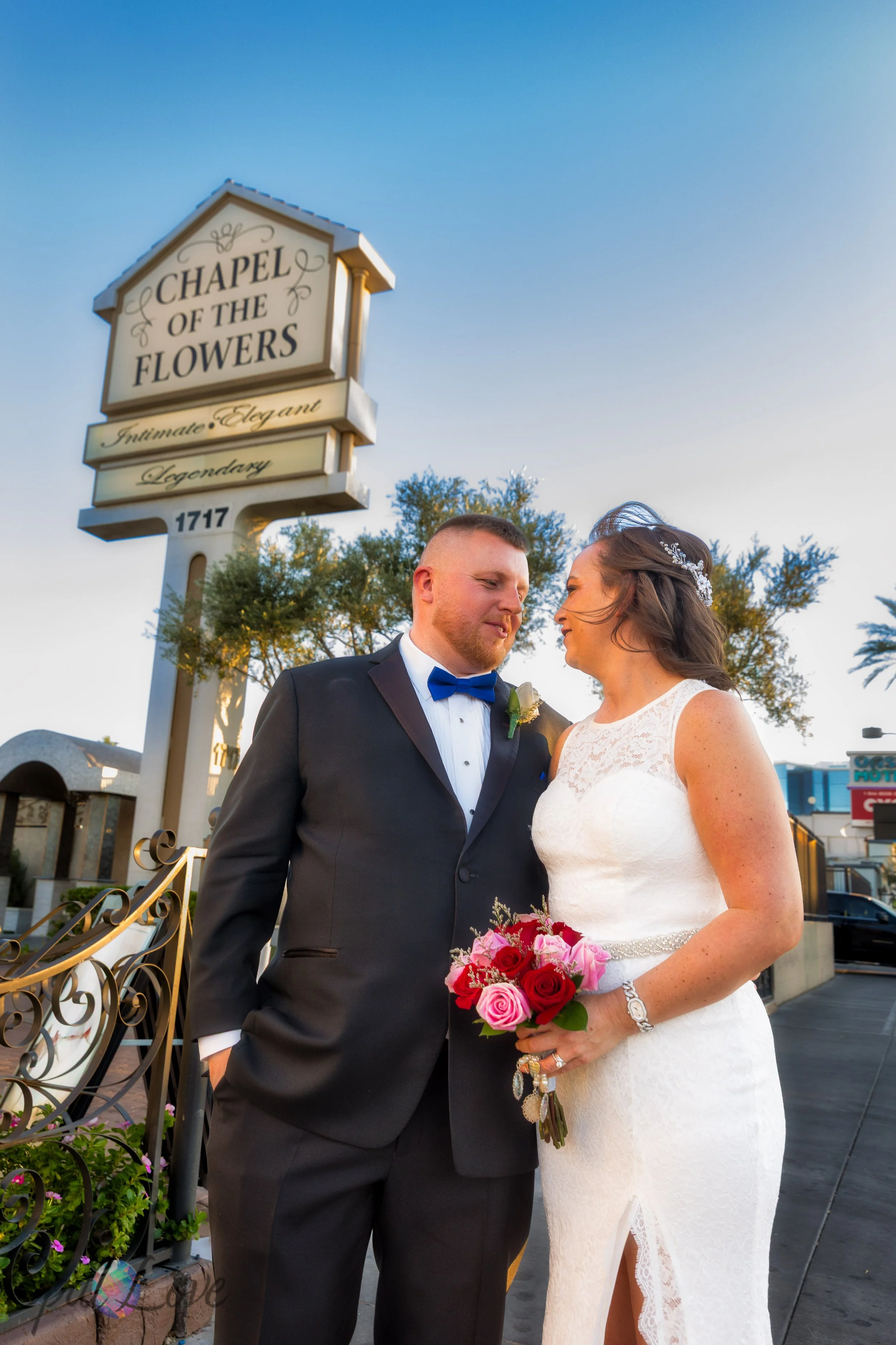 Bride and groom standing in front of the Chapel of the Flowers sign during their Las Vegas wedding.