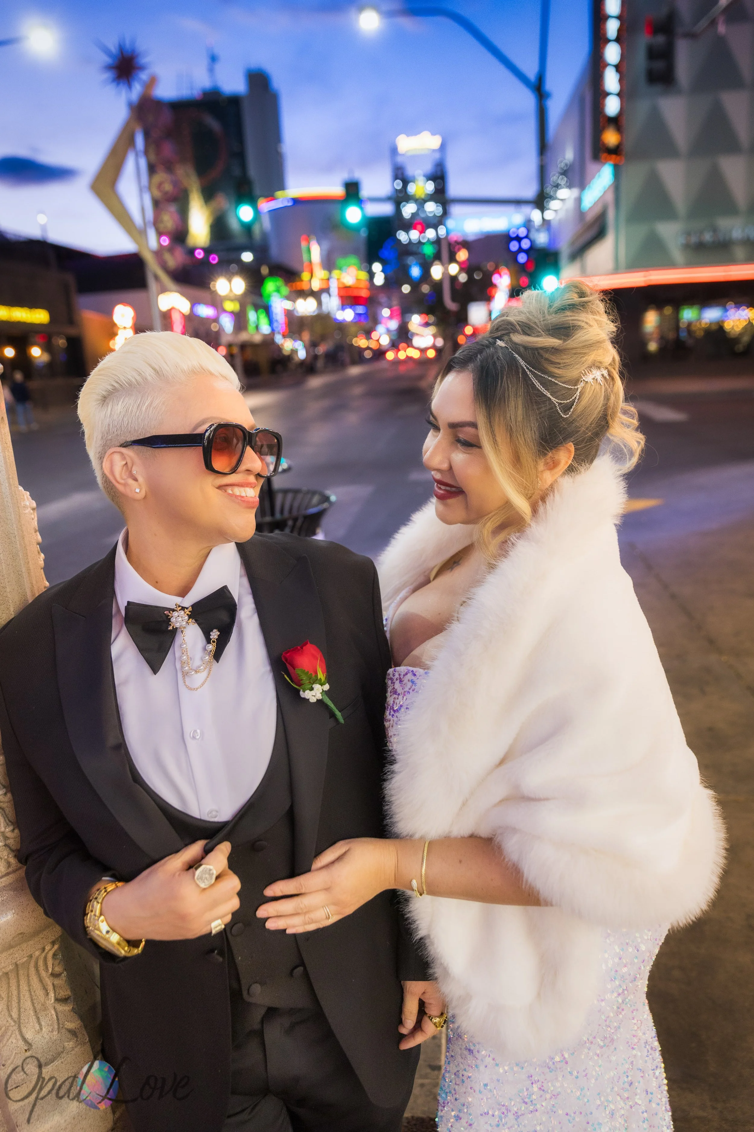 Married couple celebrating their anniversary on Fremont Street in Las Vegas with colorful neon lights glowing behind them.