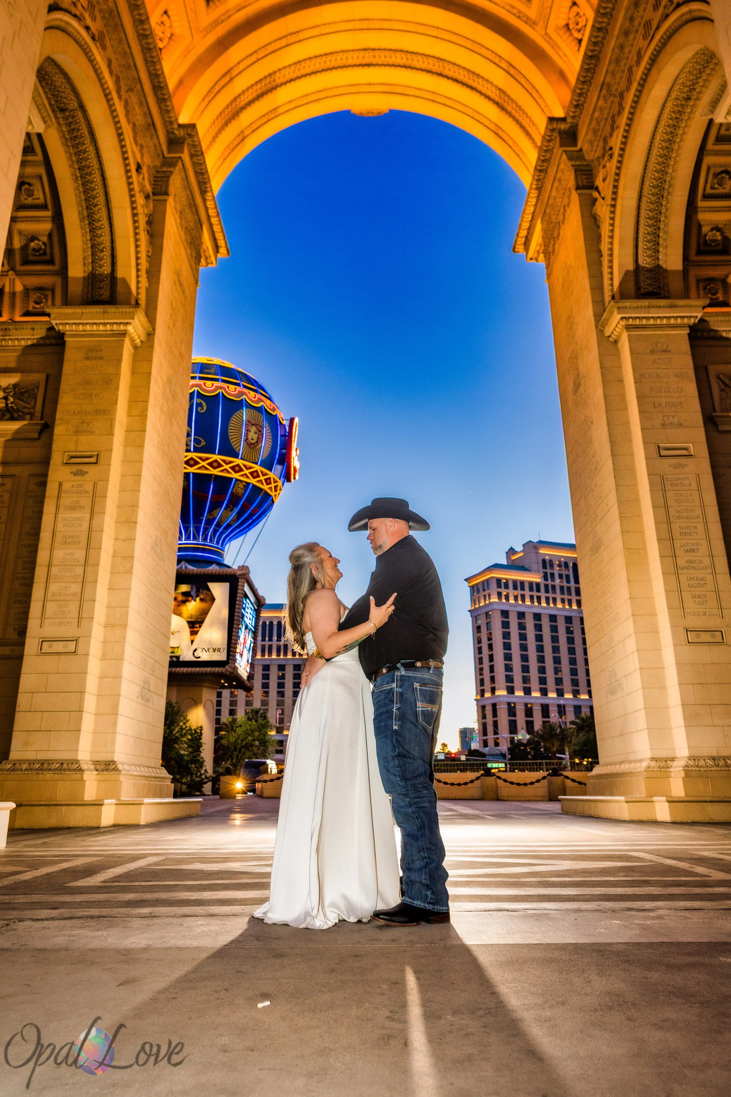 Couple embracing under archway at Paris Las Vegas with Strip architecture