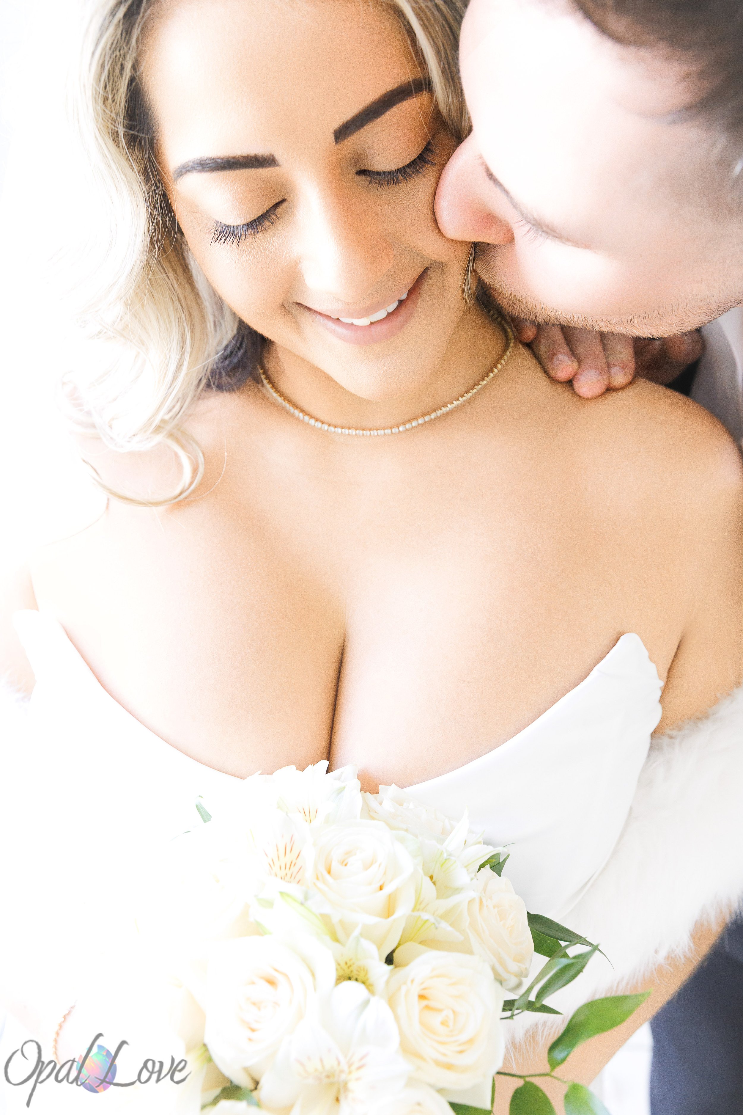 Close up portrait of bride smiling while groom kisses her cheek at a Las Vegas chapel wedding.