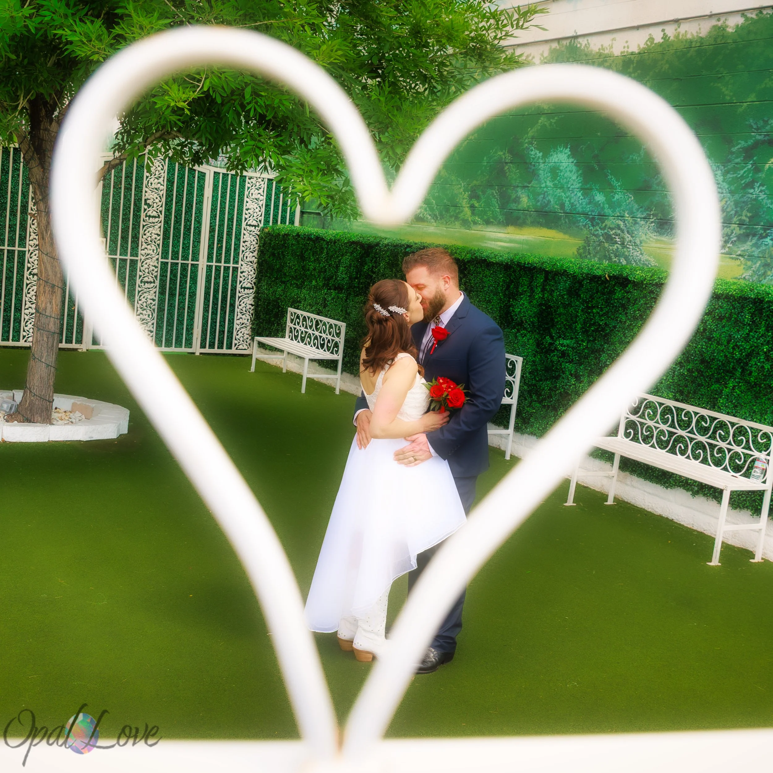 Newlywed couple kissing through a heart-shaped frame at the Little White Wedding Chapel in Las Vegas.